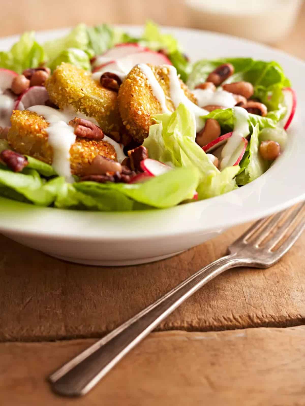 Fried green tomato salad on a white plate.