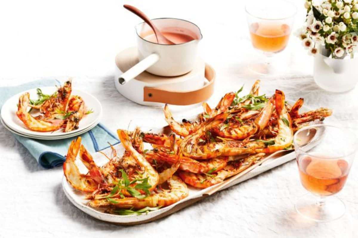 Barbecued prawns with rose butter sauce on a white tray.