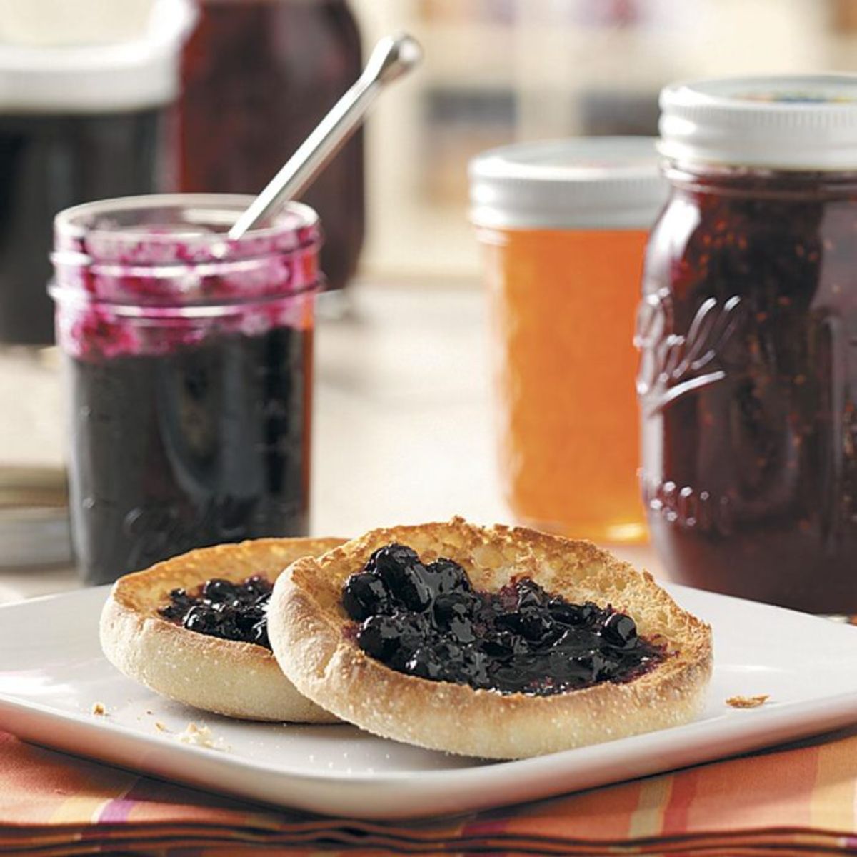 Cinnamon blueberry jam in a glass jar on a piece of bread.