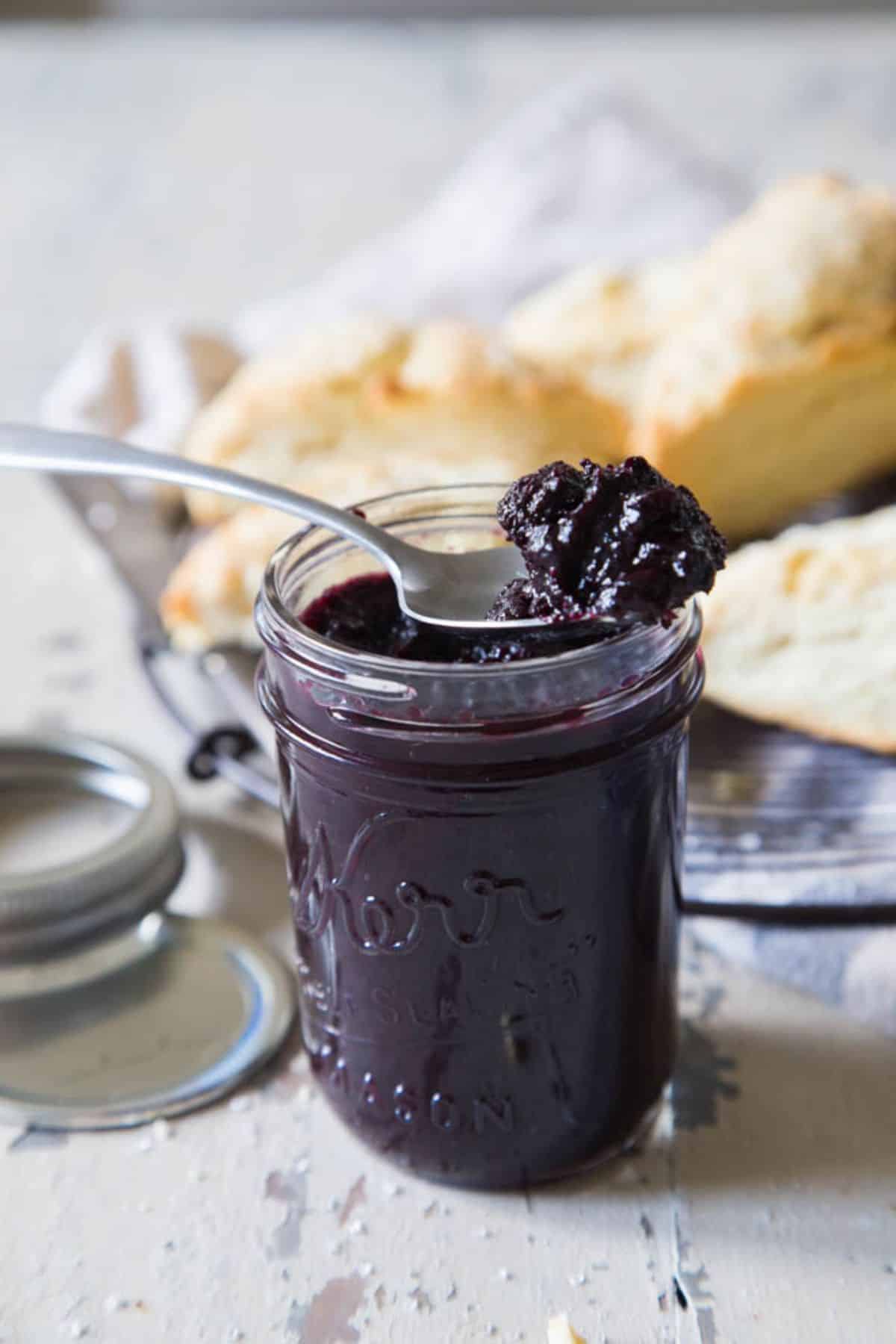 Blueberry butter in a glass jar picked with a spoon.