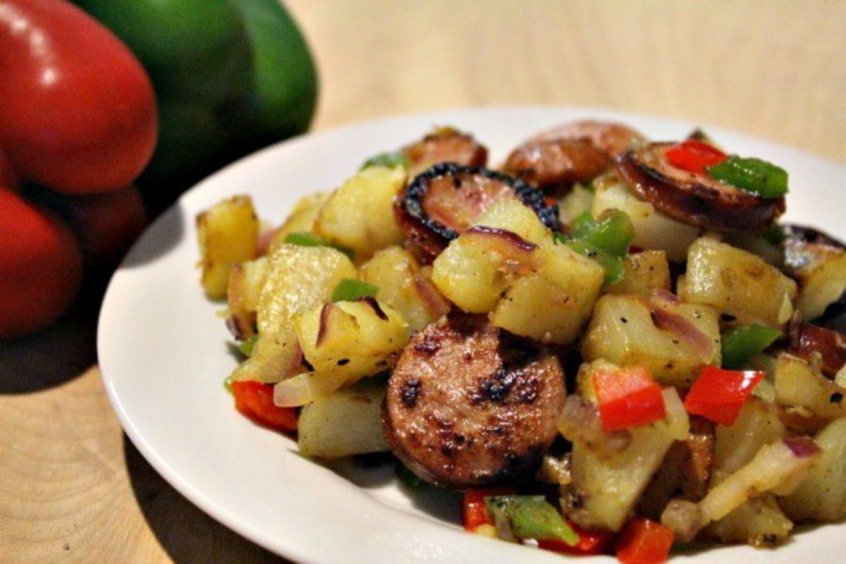 Smoked sausage, pepper, and potato hash on a white plate.