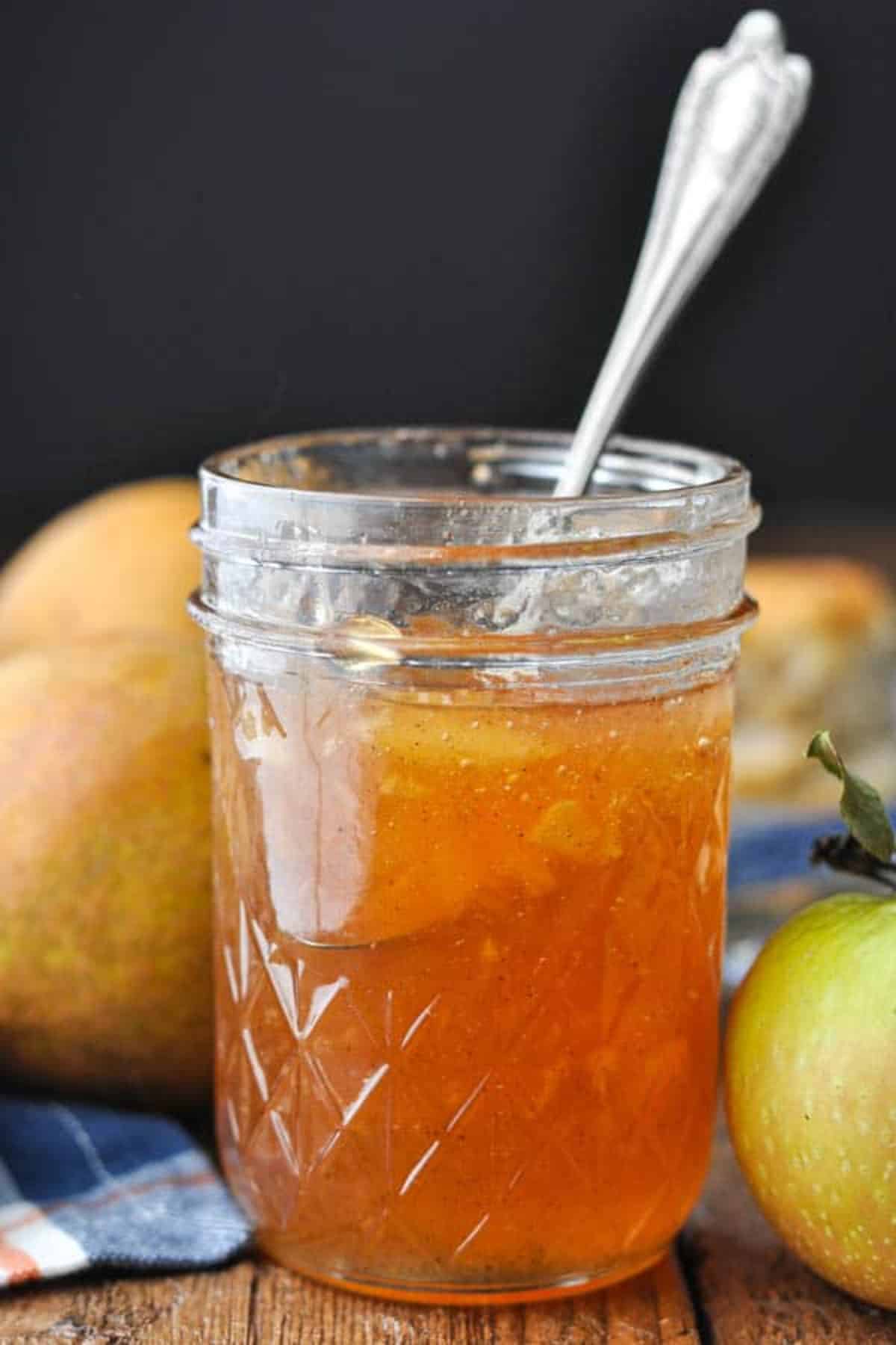 Delicious spiced apple pear jam in a glass jar with a spoon.
