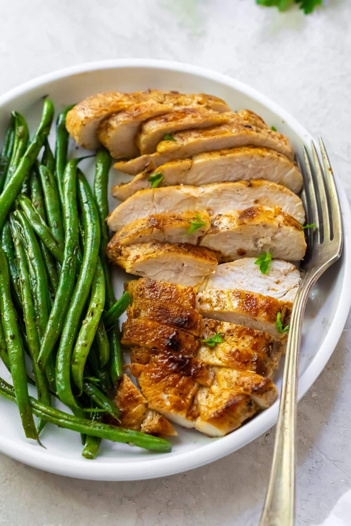 Best blackstone chicken breasts with veggies on a white plate.