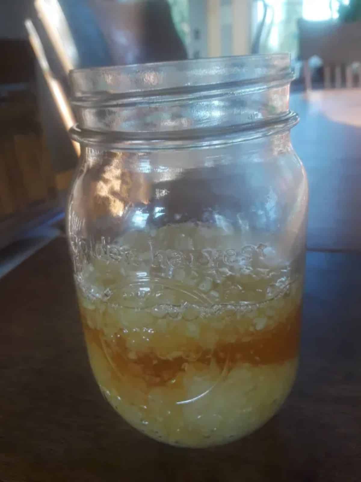 Fermented garlic honey sauce in a glass jar.