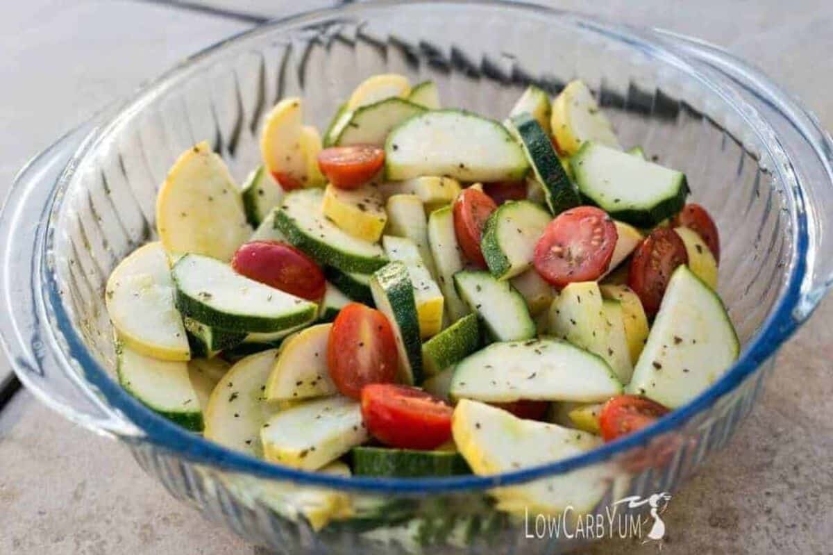 Summer zucchini and squash salad with tomatoes in a glass bowl.