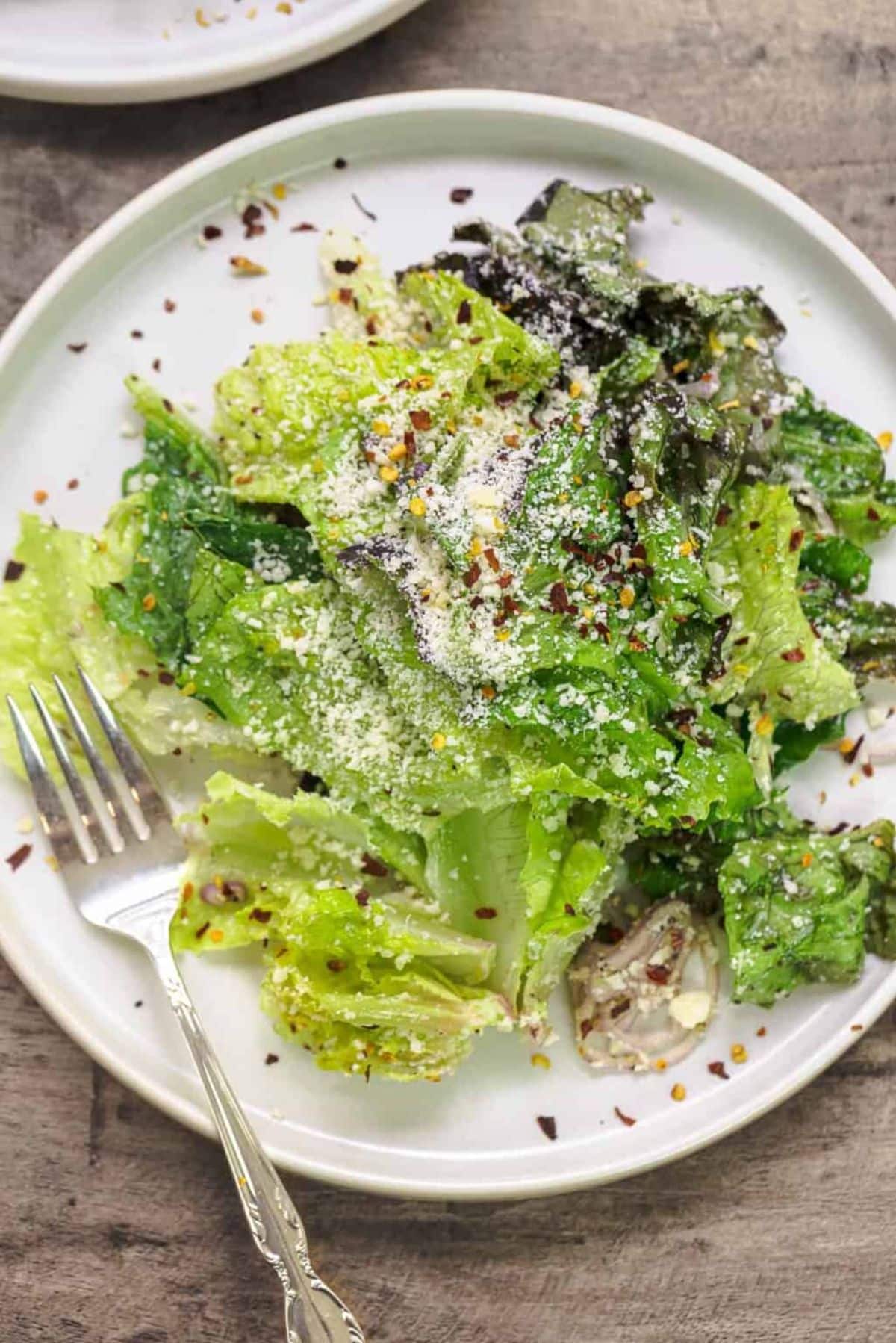 Healthy 5-minute lemon parmesan lettuce salad on a white plate with a fork.