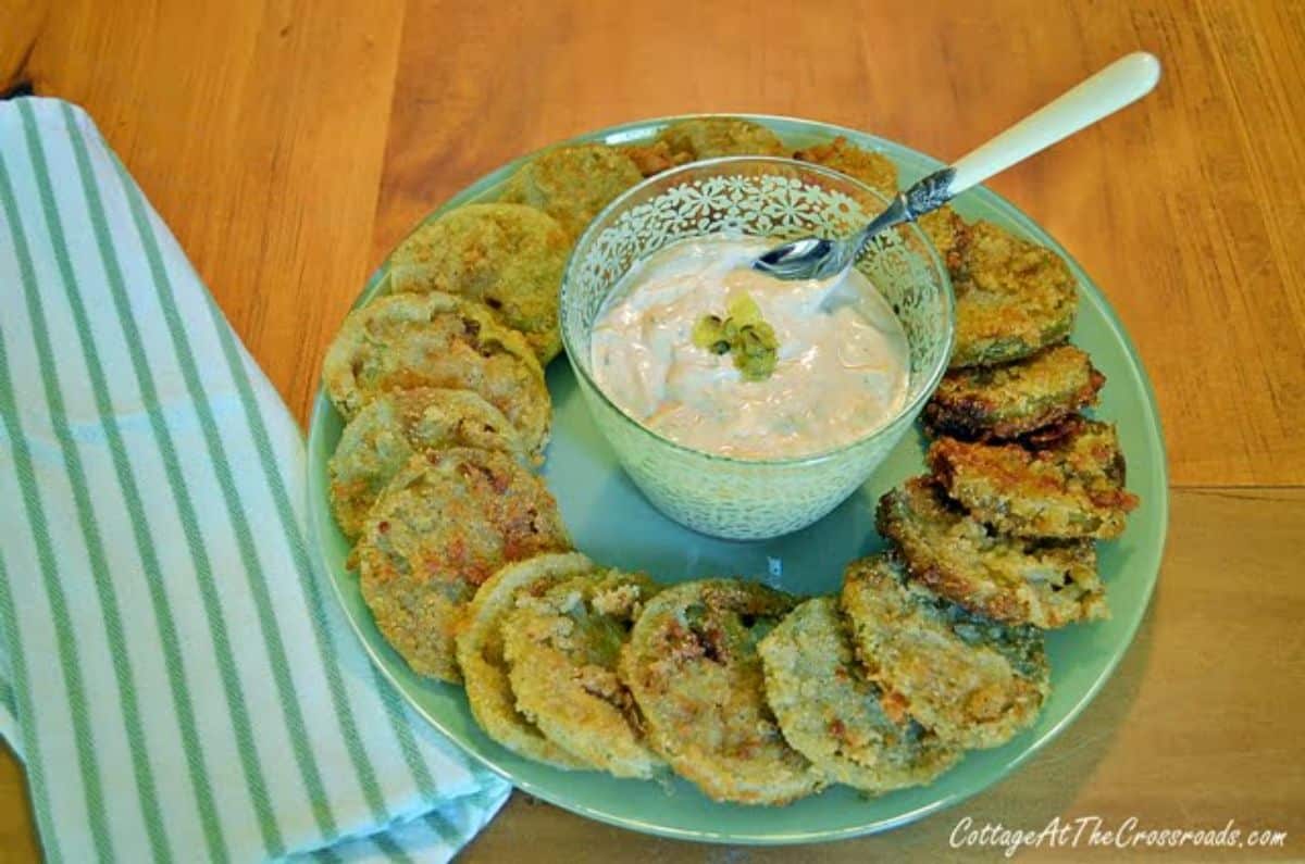 Fried green tomatoes with remoulade sauce on a green plate.