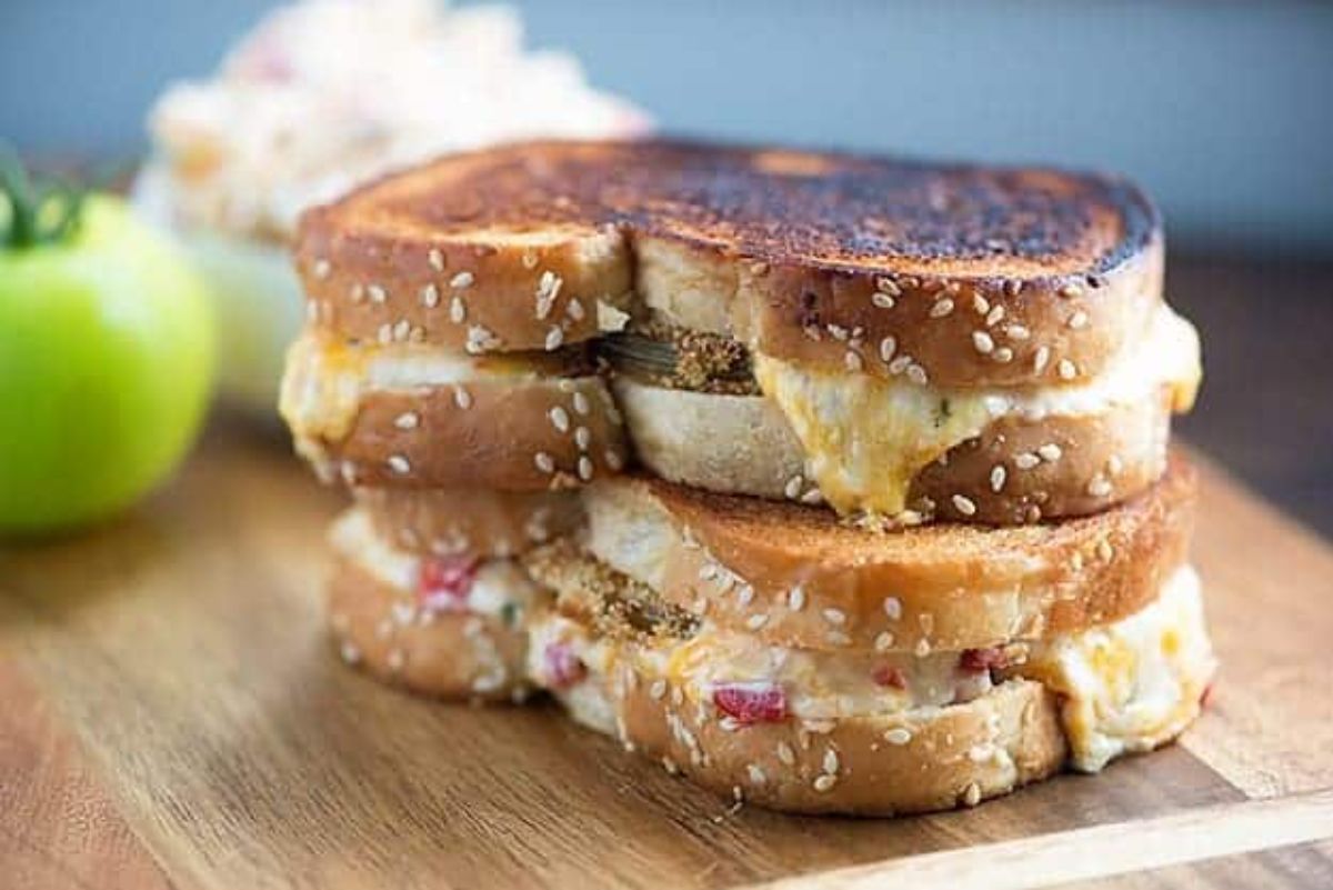 Green tomato and pimento cheese sandwich on a wooden cutting board.