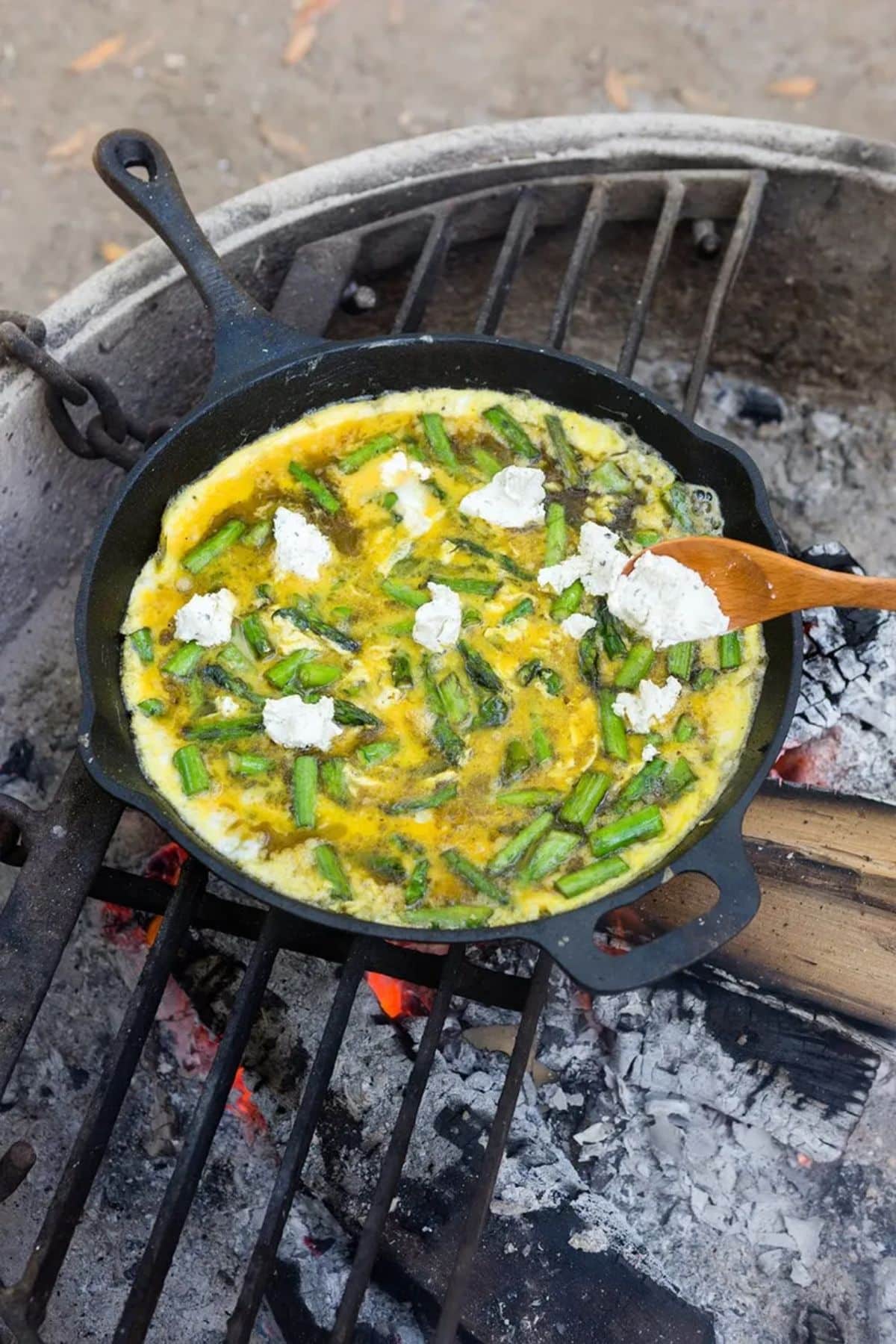 Asparagus and goat cheese frittata on a black skillet.