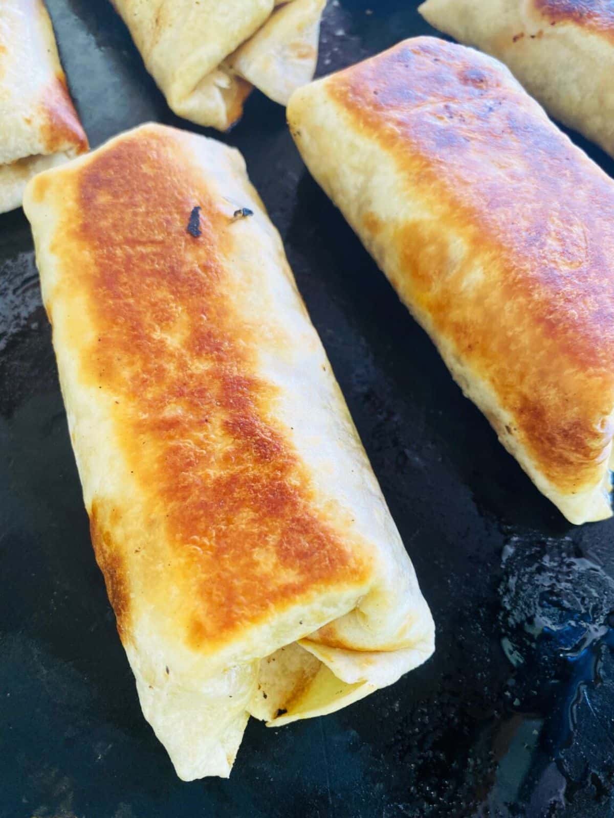 Blackstone chorizo breakfast burritos on a black skillet.