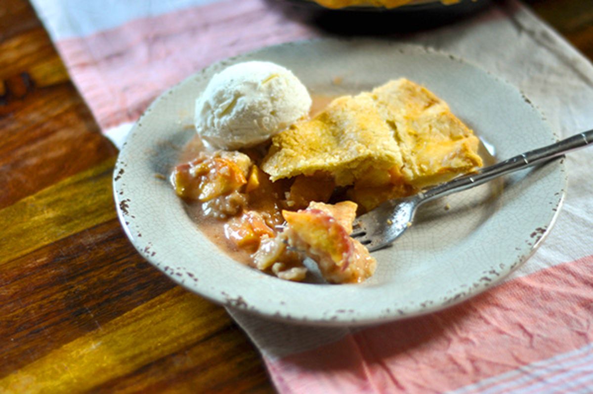 Delicious juicy peach pie with a lard crust on a plate with a fork.