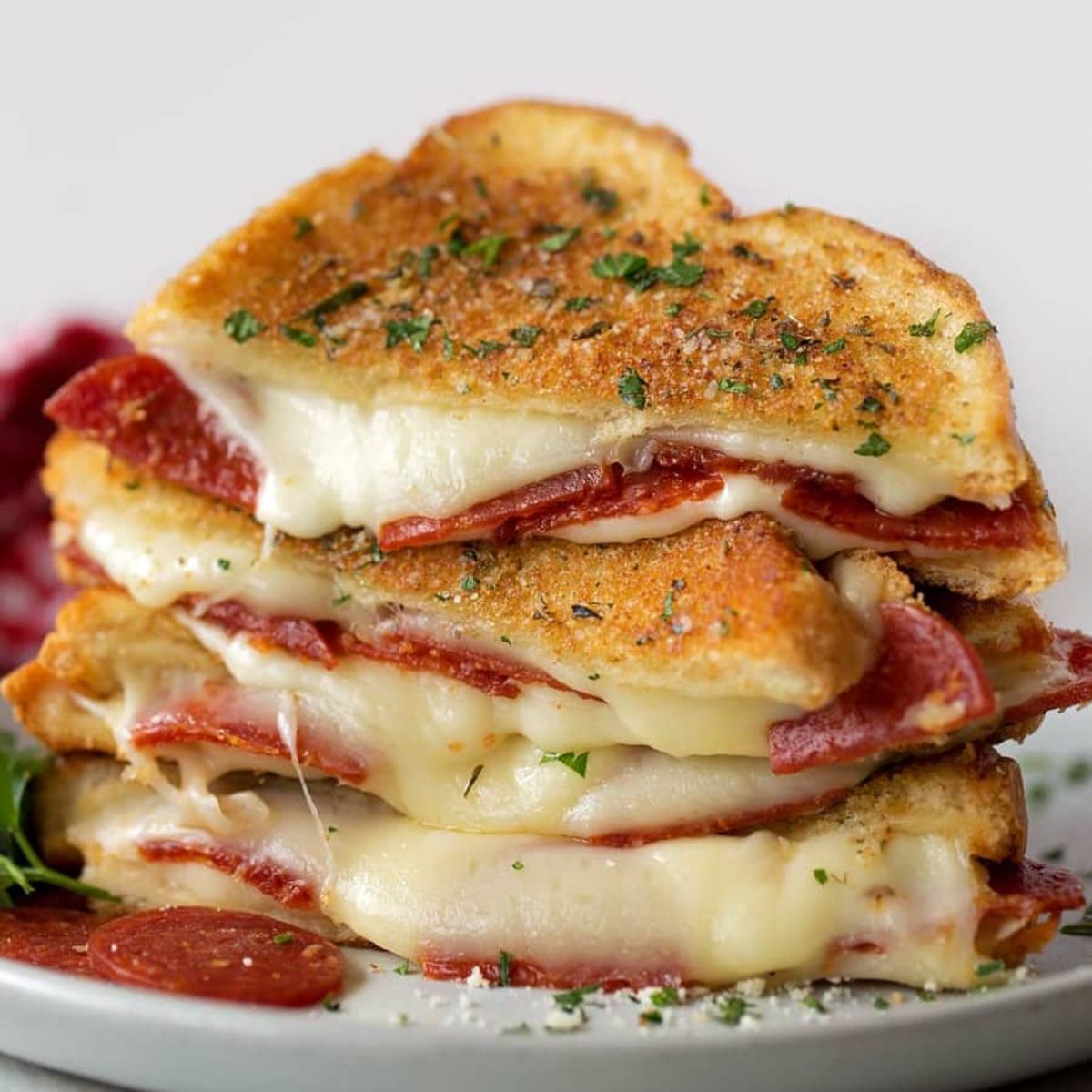 Juicy pepperoni pizza grilled cheese on a white plate.