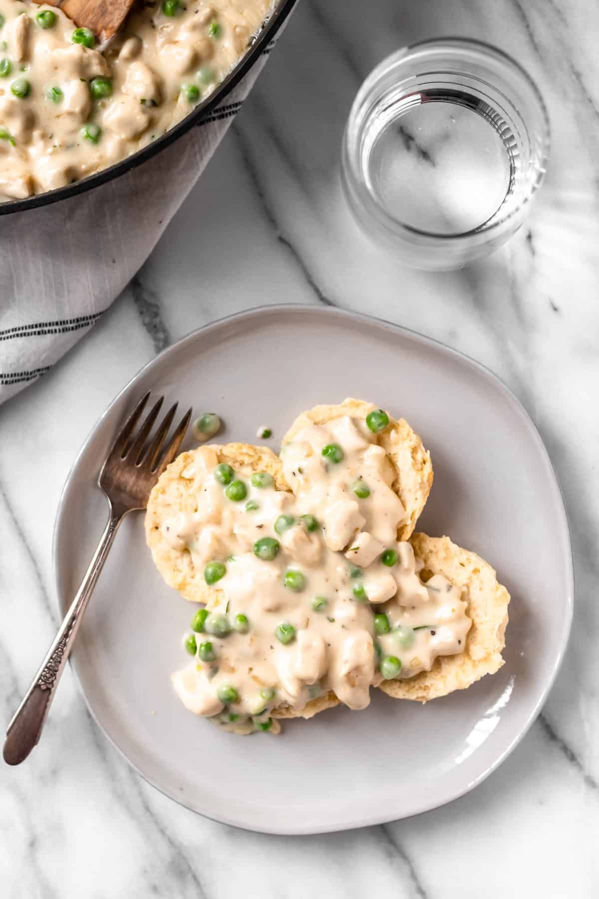 Delicious creamed chicken over biscuits on a gray plate with a fork.