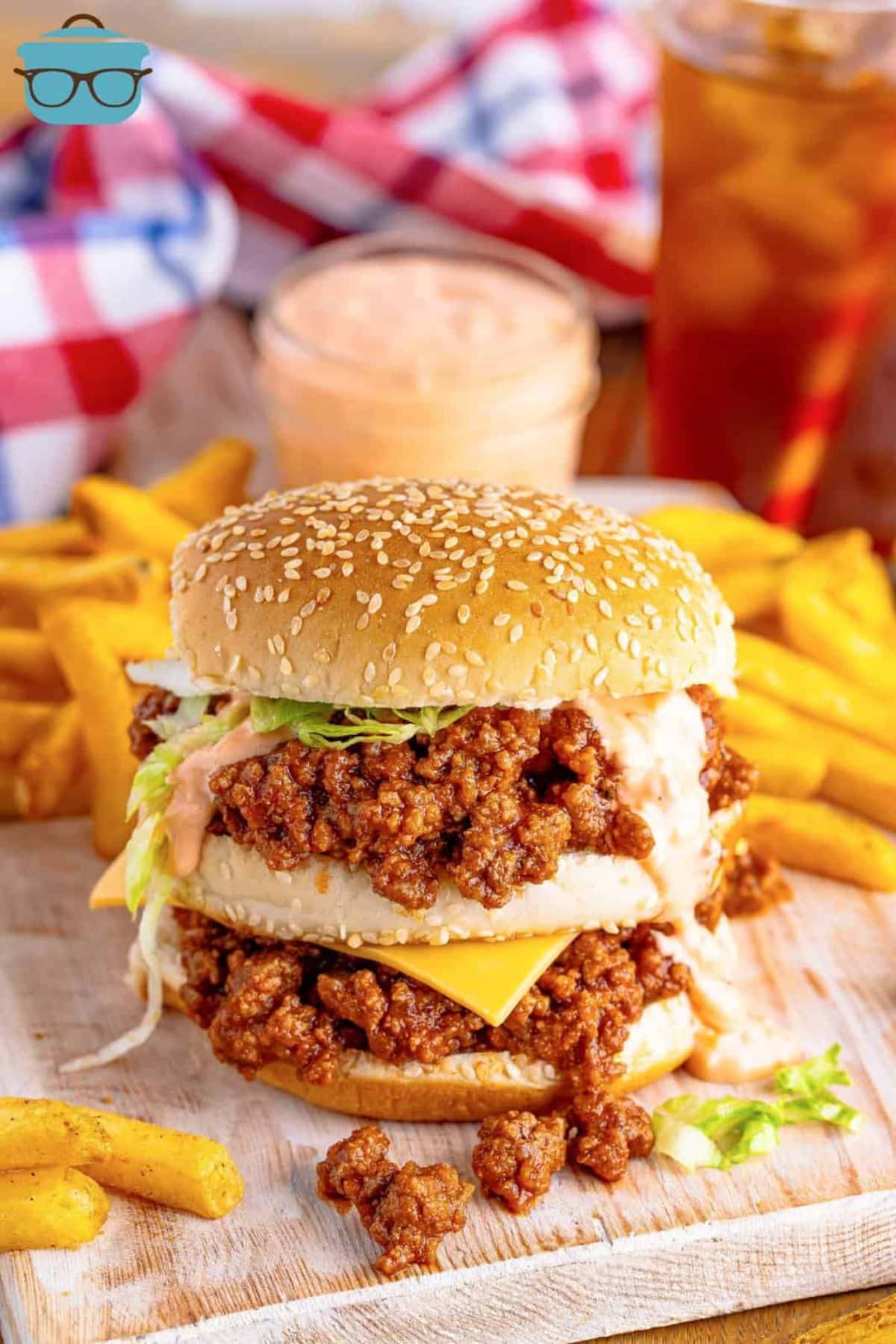 Big mac sloppy joes with fries on a wooden cutting board.