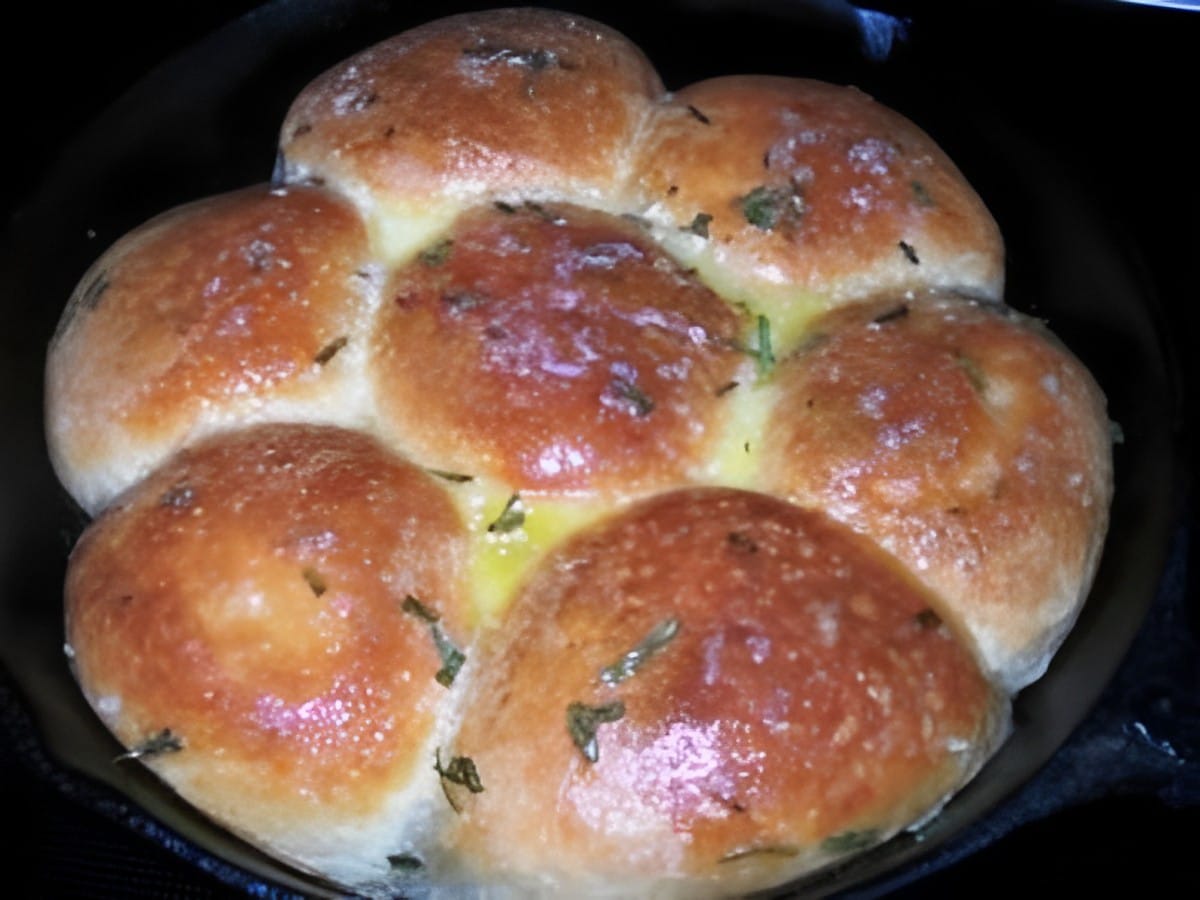 Flavorful pioneer woman’s buttered rosemary dinner rolls in a baking tray.