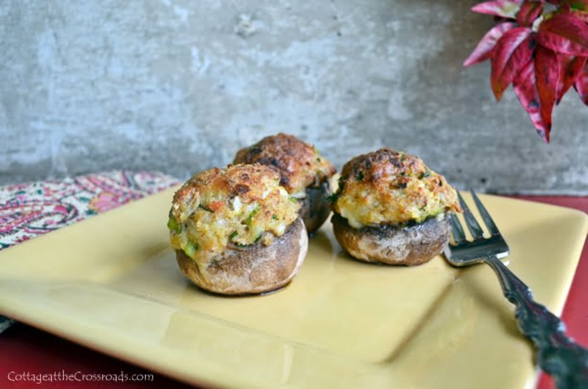 Scrumptious lowcountry crab and pimento cheese stuffed mushrooms on a yellow plate with a fork.