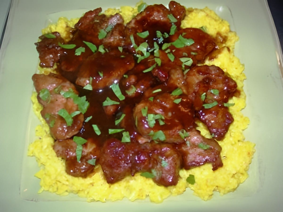 Juicy pork medallions with yellow rice on a green plate.