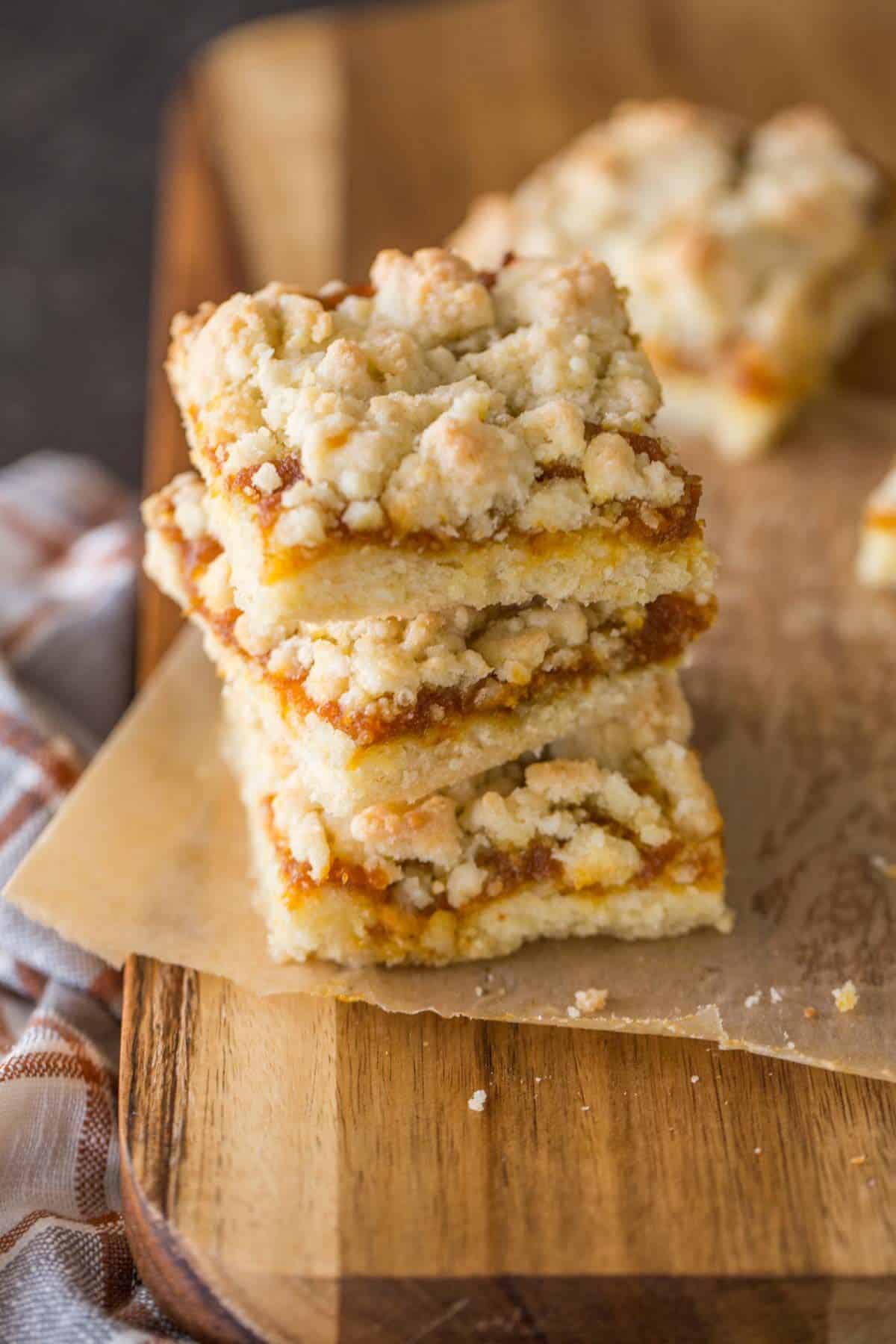 A pile of pumpkin butter crumb bars on a wooden tray.