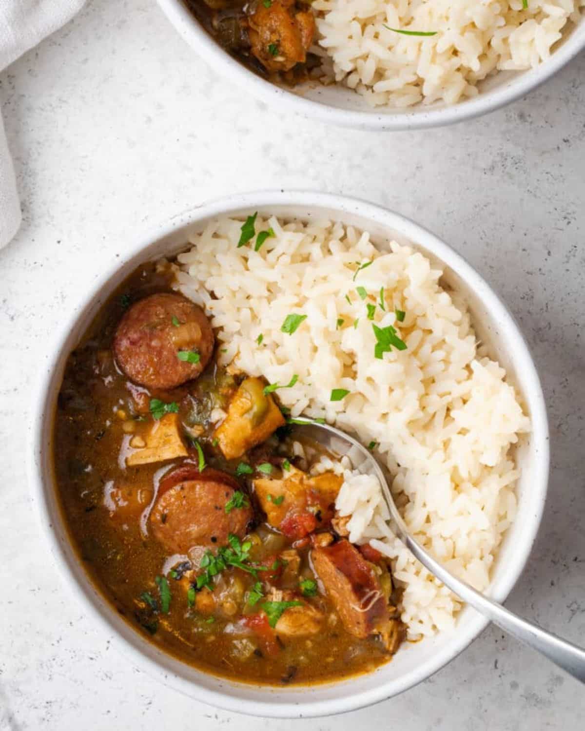 Delicious chicken and sausage gumbo in a white bowl with a spoon.