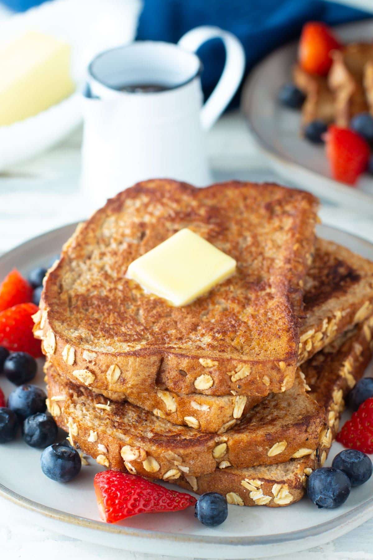 A pile of egg white french toasts on a plate with fruits.