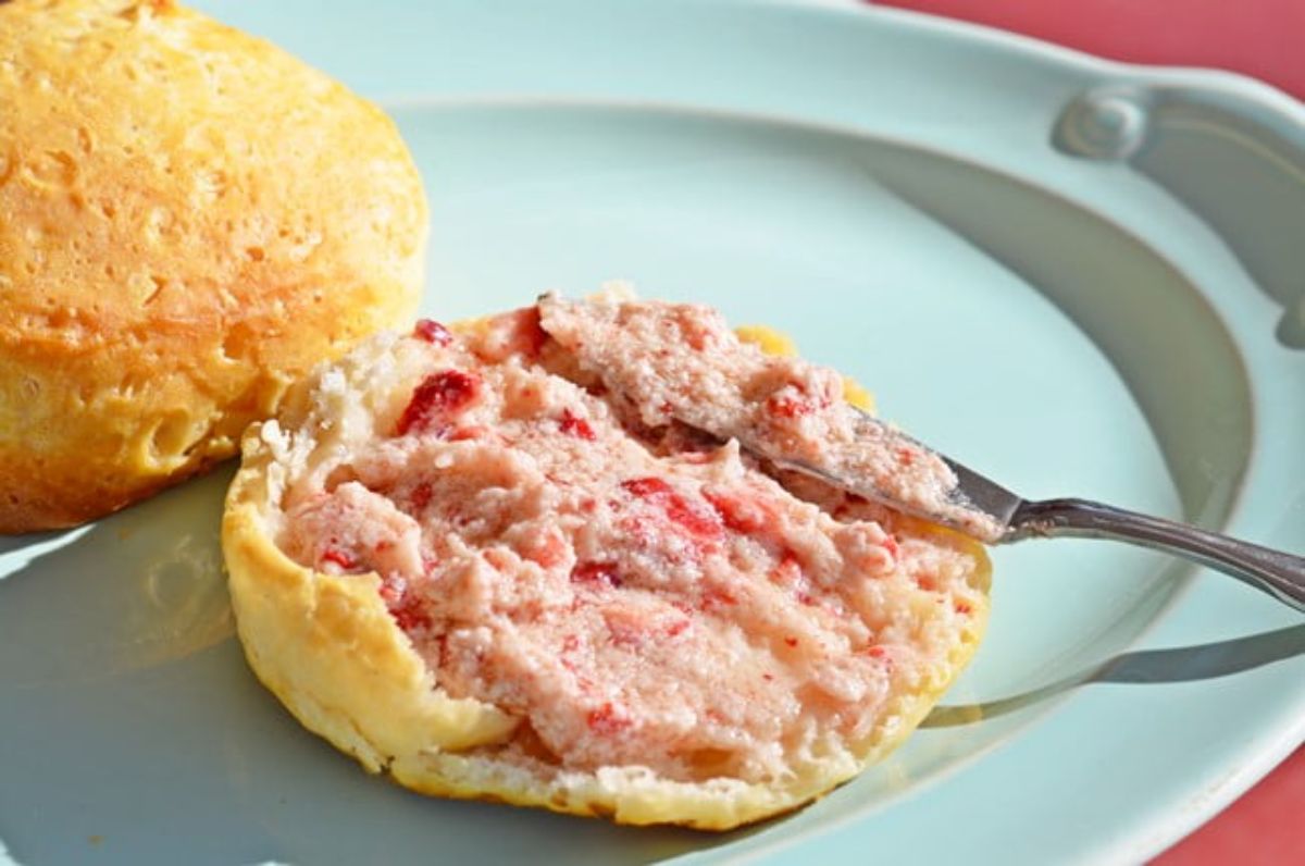 Strawberry honey butter spread on a bun with a knife.