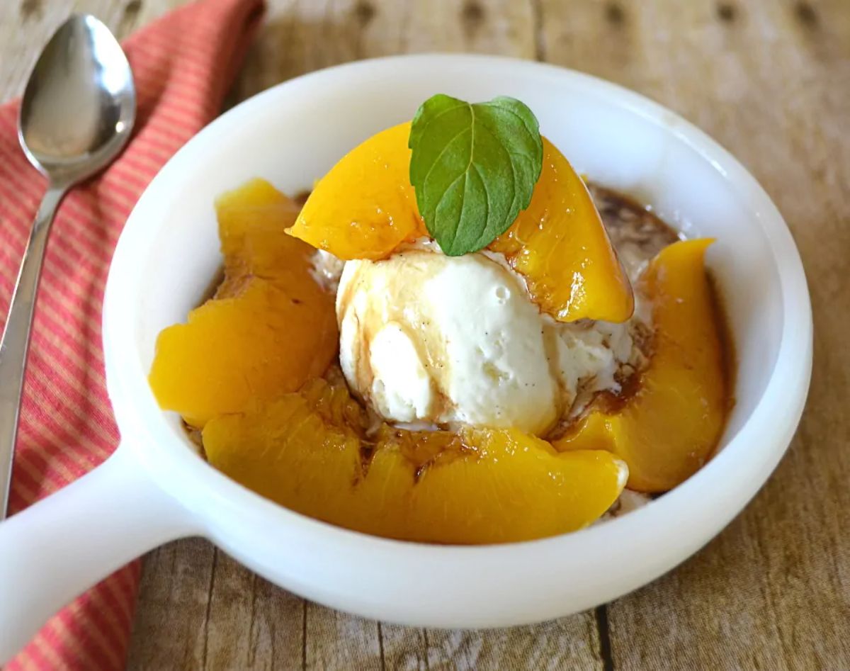 Delicious peach ice cream sundae in a white bowl.