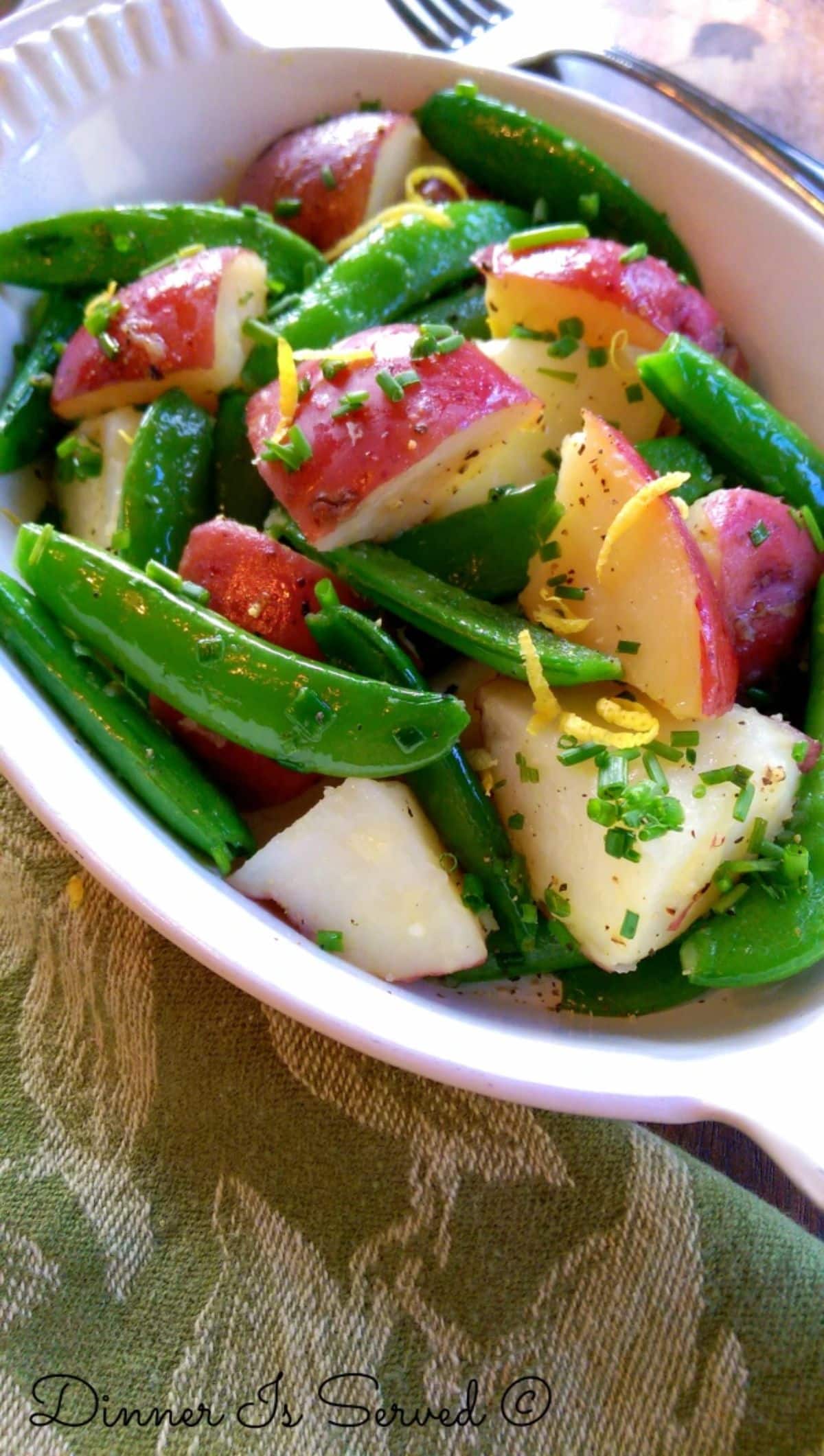 Healthy sauteed potatoes with snap peas in a white bowl.