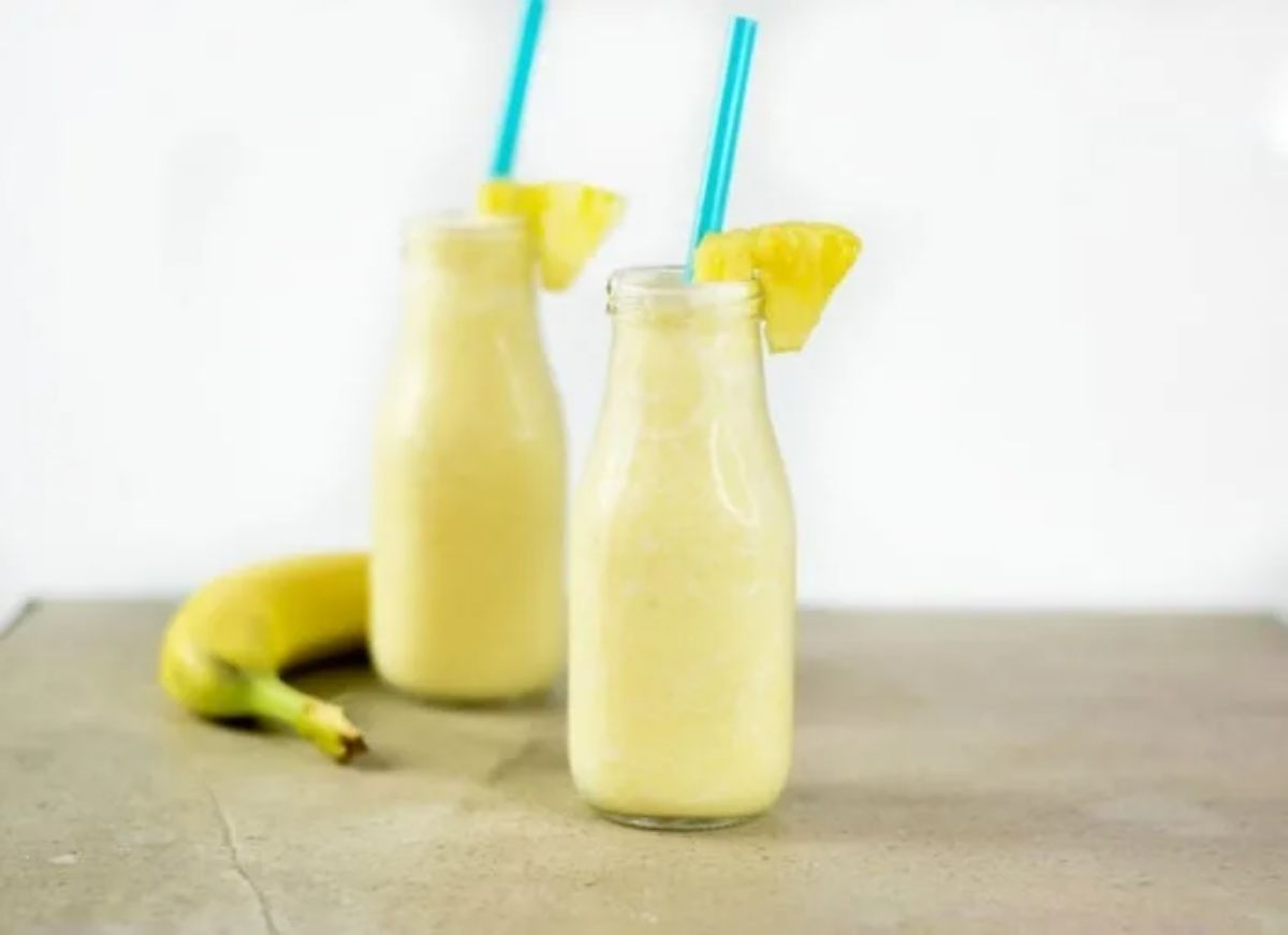 Delicious pineapple apple tropical smoothie in glass jars with straws.