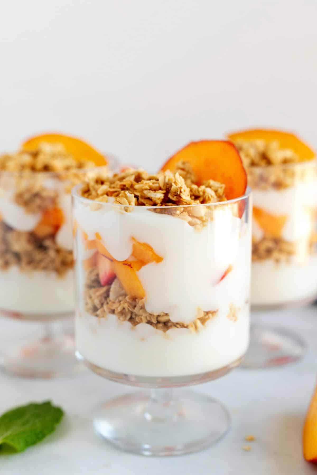 Creamy peach yogurt parfaitsin tall glasses.