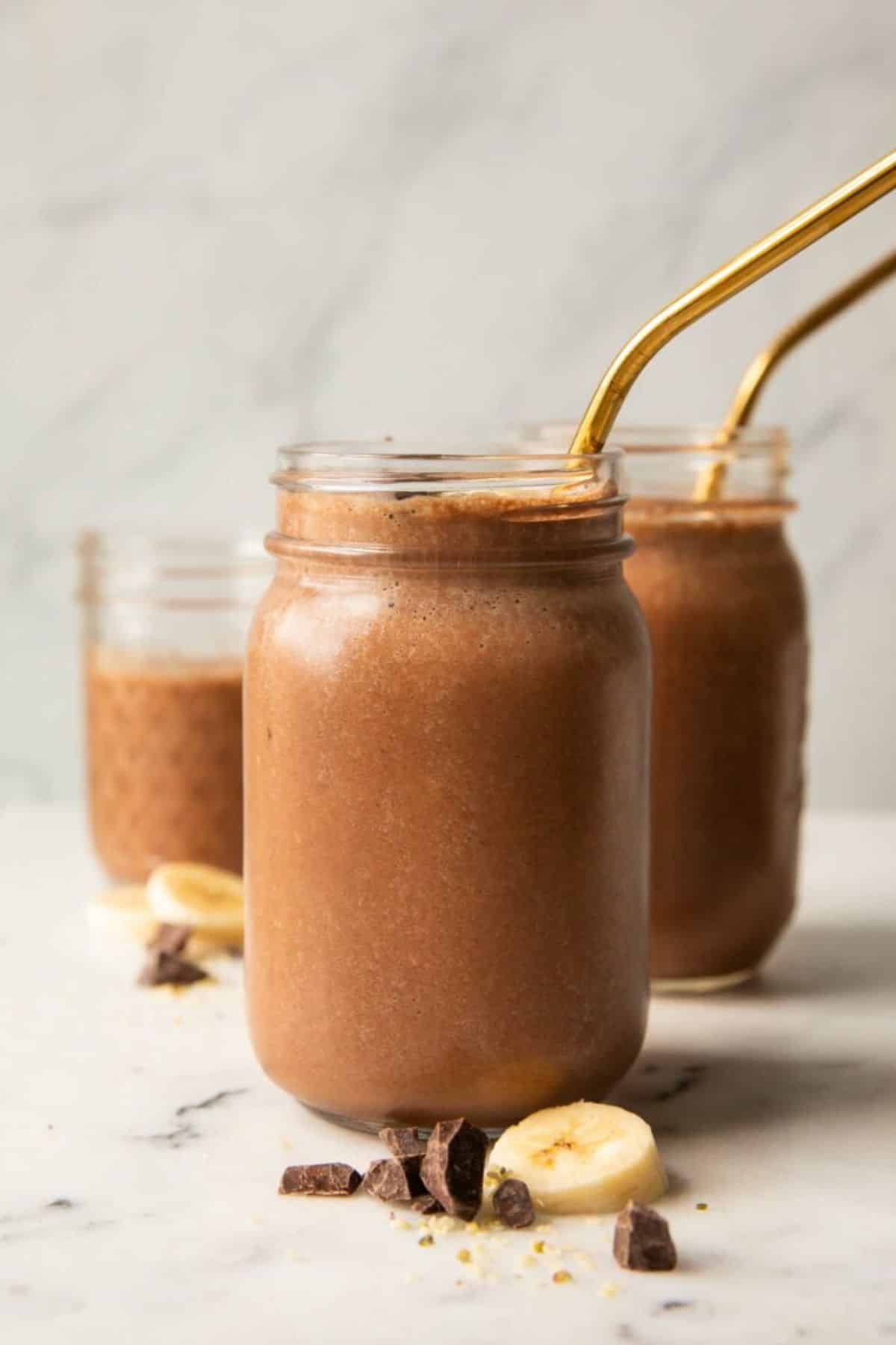 Healthy chocolate banana smoothie in glass jars with straws.