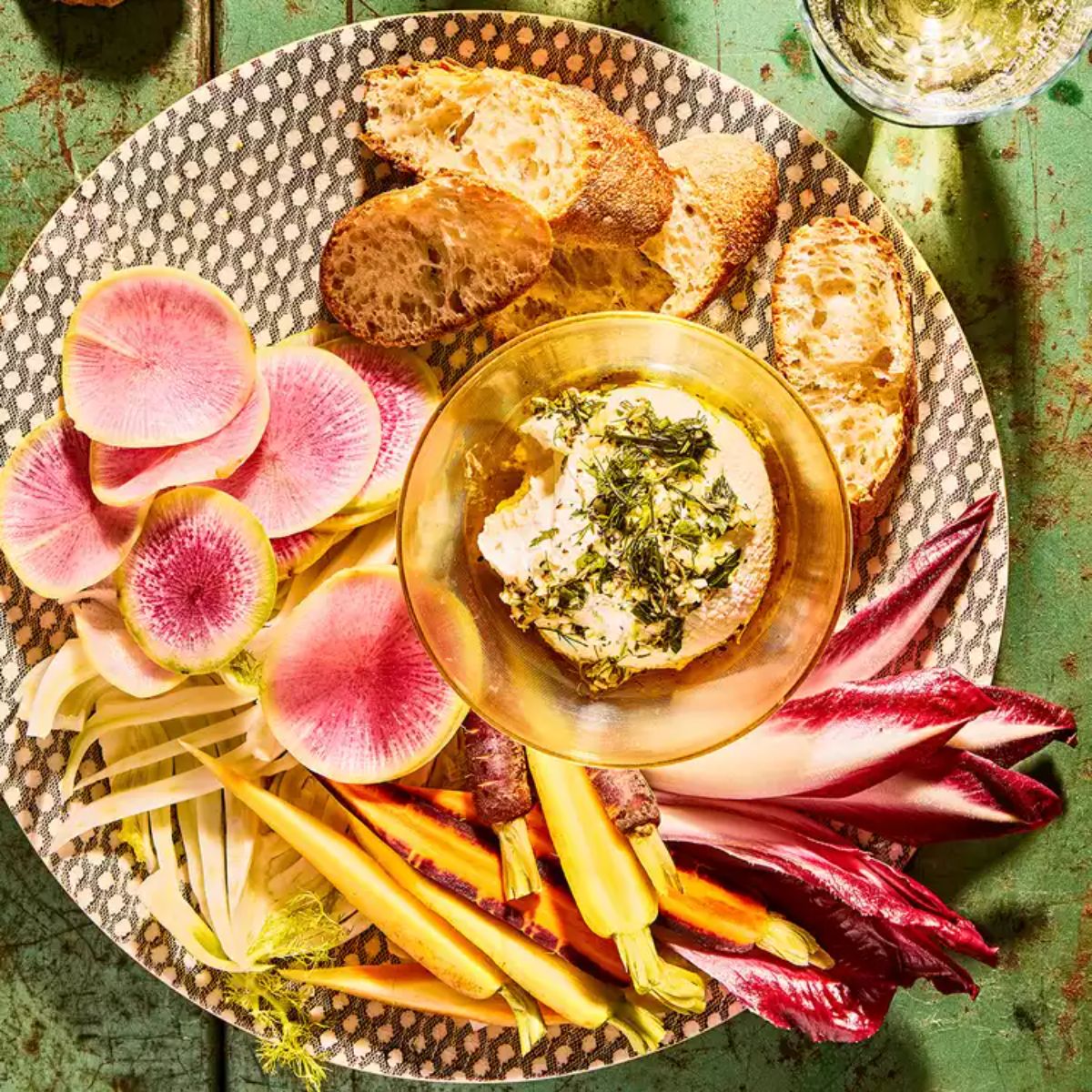 A bowl of marinated yogurt cheese with veggies on a plate.