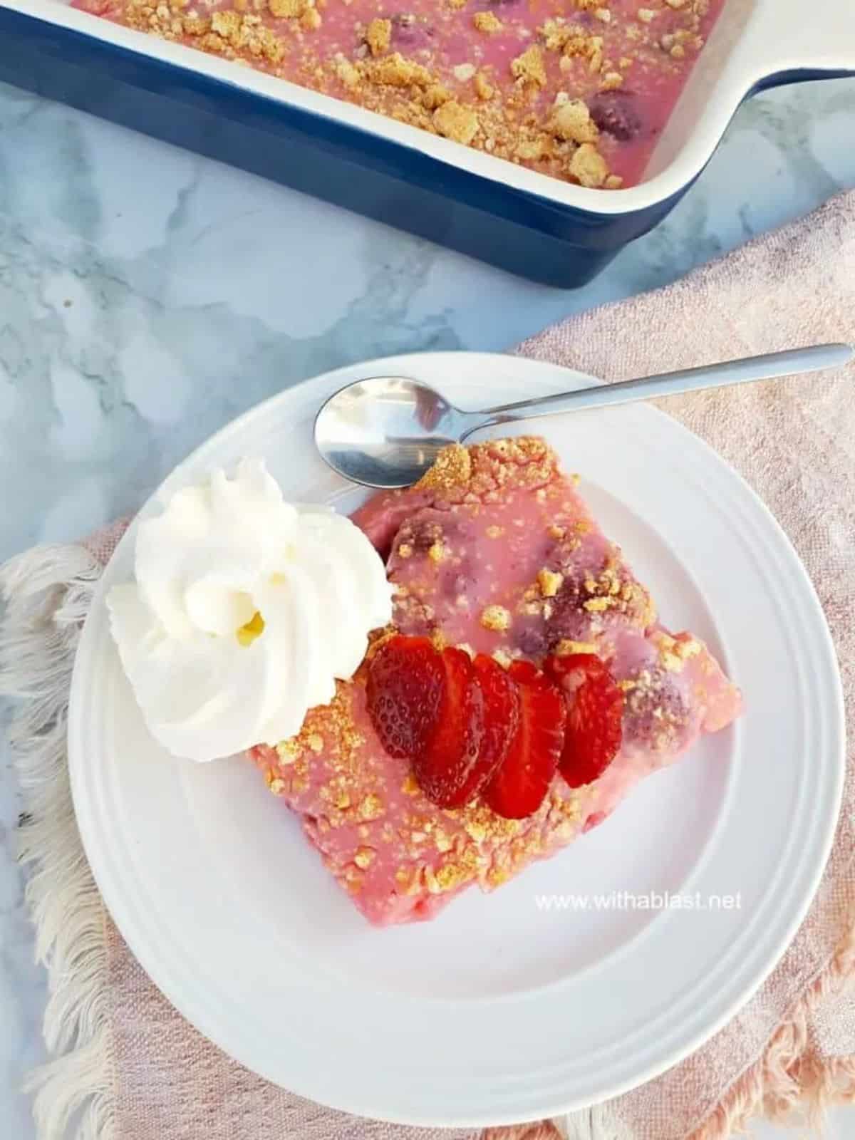 A piece of strawberry yogurt tart on a white plate with a spoon.