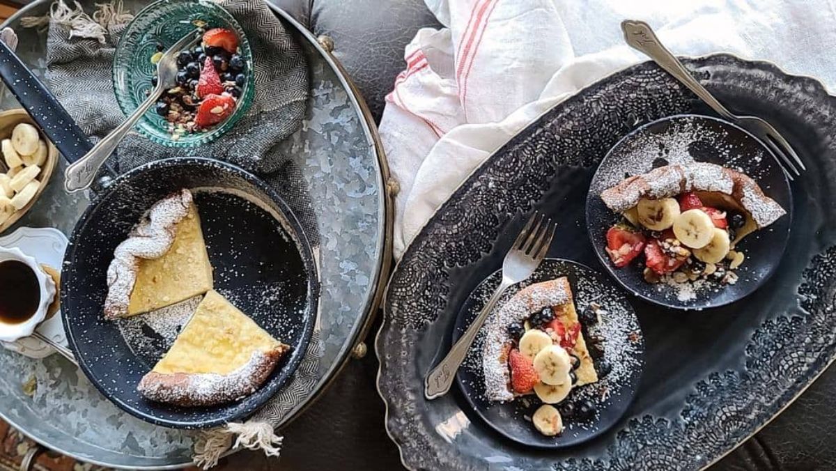 Flavorful dutch baby pancakes on black plates.