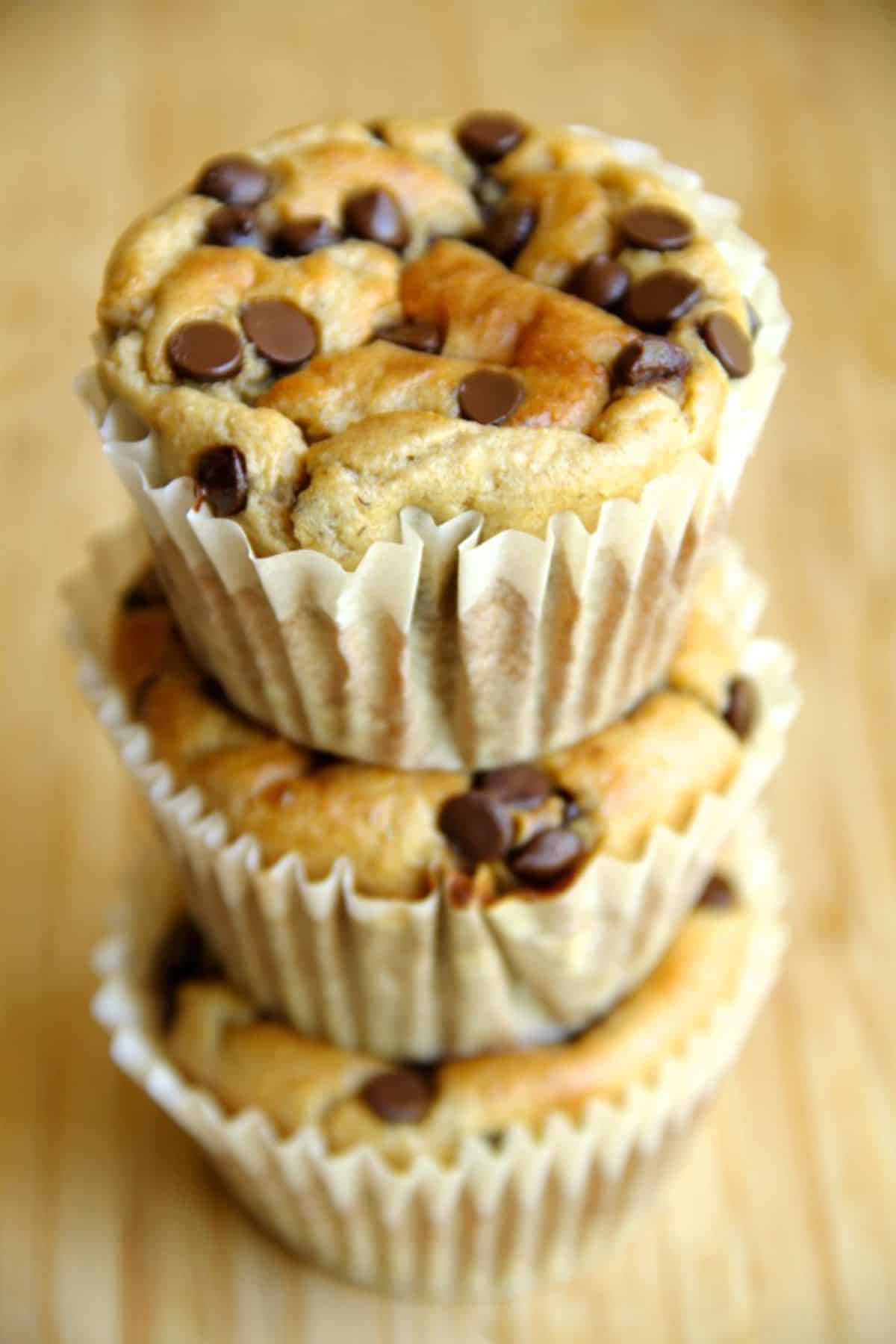 A pile of banana oat greek yogurt muffins on a wooden table.