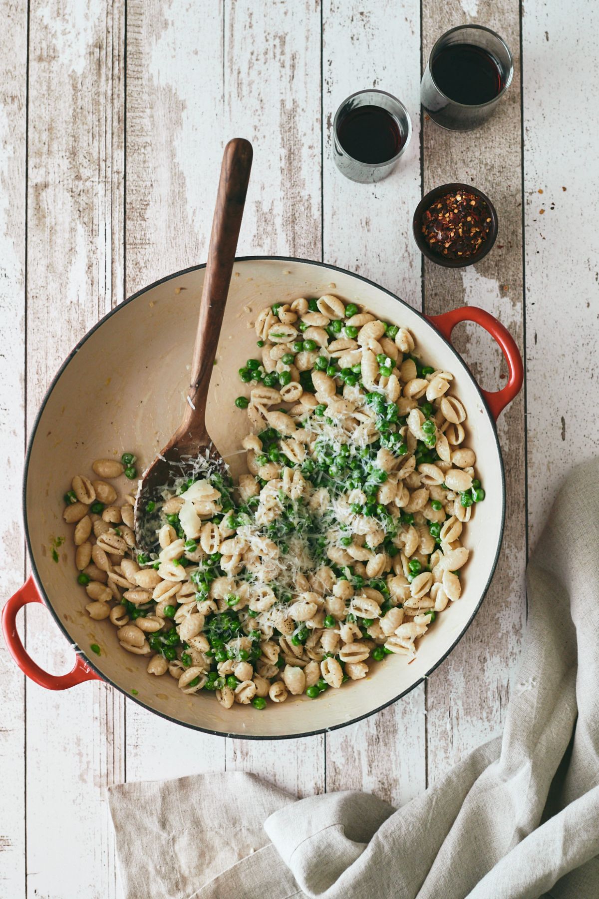 Tasty pea pasta in a bowl with a wooden spoon.