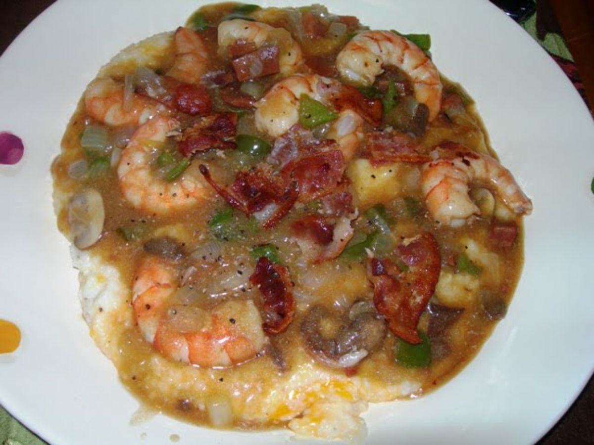 Juciy shrimp and grits on a white plate.