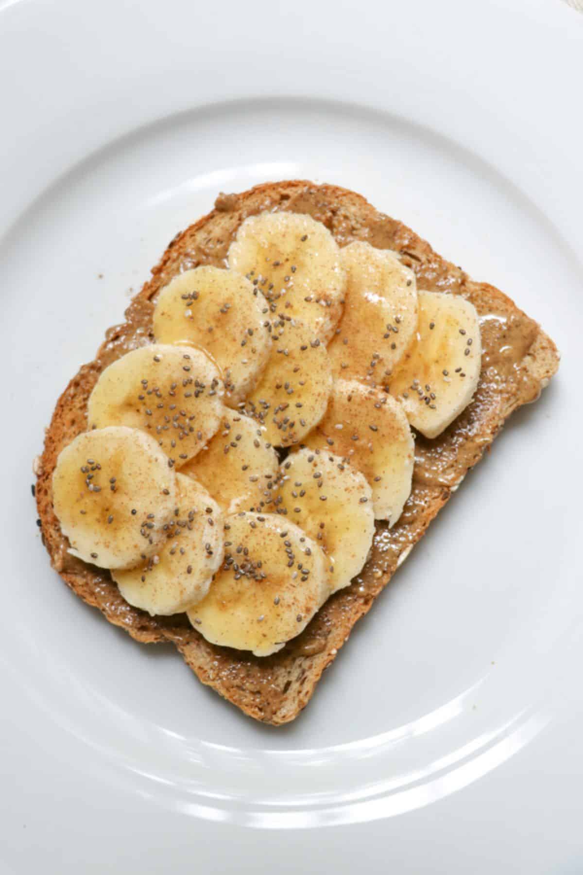 Tasty almond butter banana honey toast on a white plate.