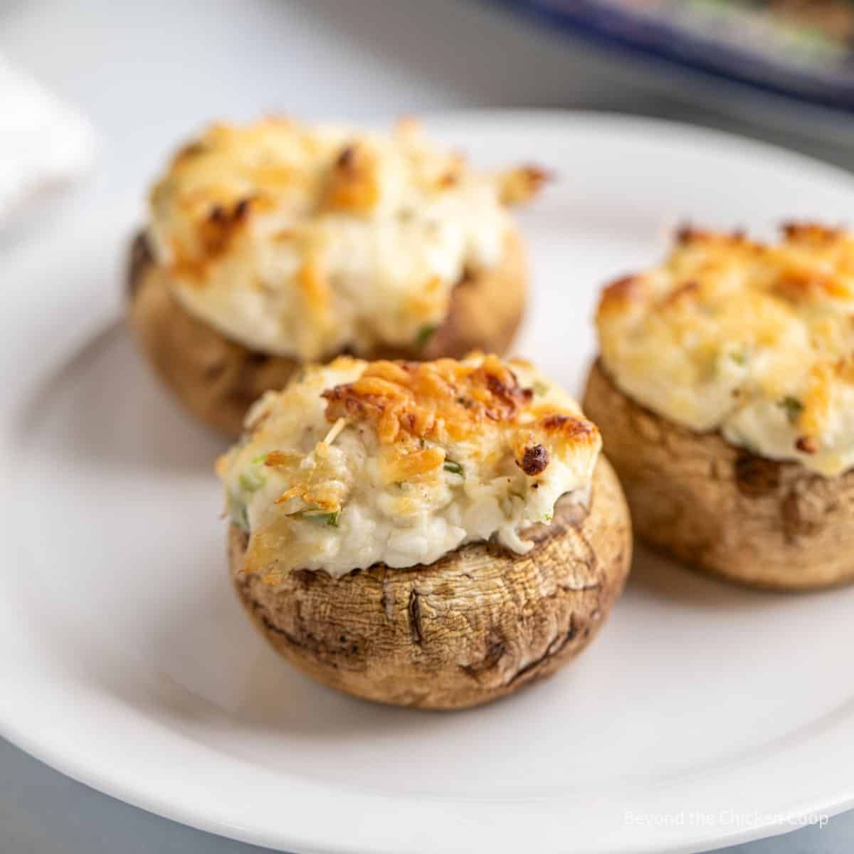 Three crunchy crab stuffed mushrooms on a white plate.