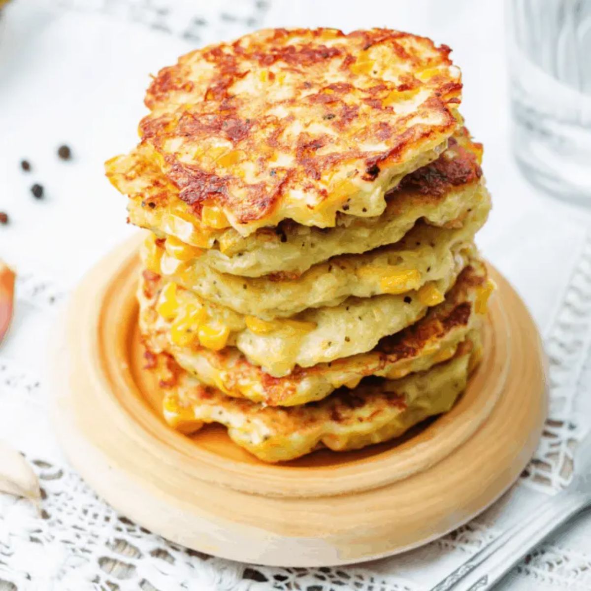 A pile of quick and easy corn fritters on a wooden plate.