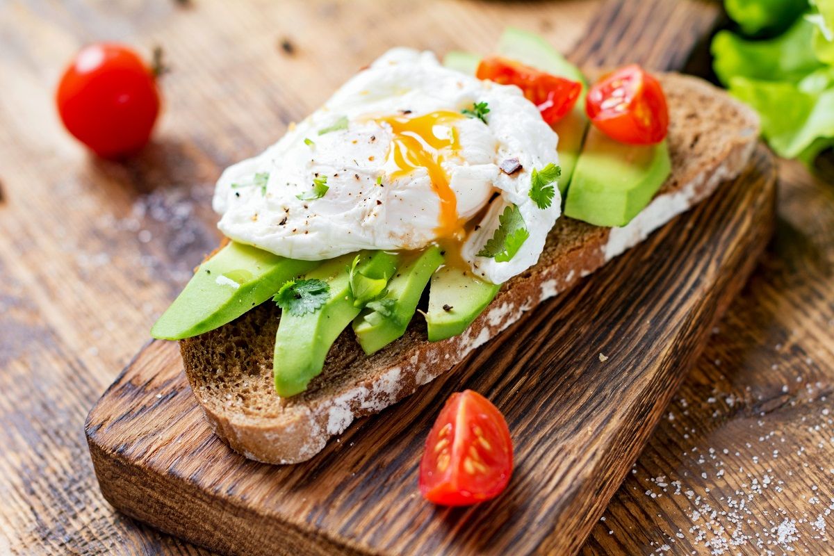 Mouth-watering fancy avocado toast on a wooden cutting board.