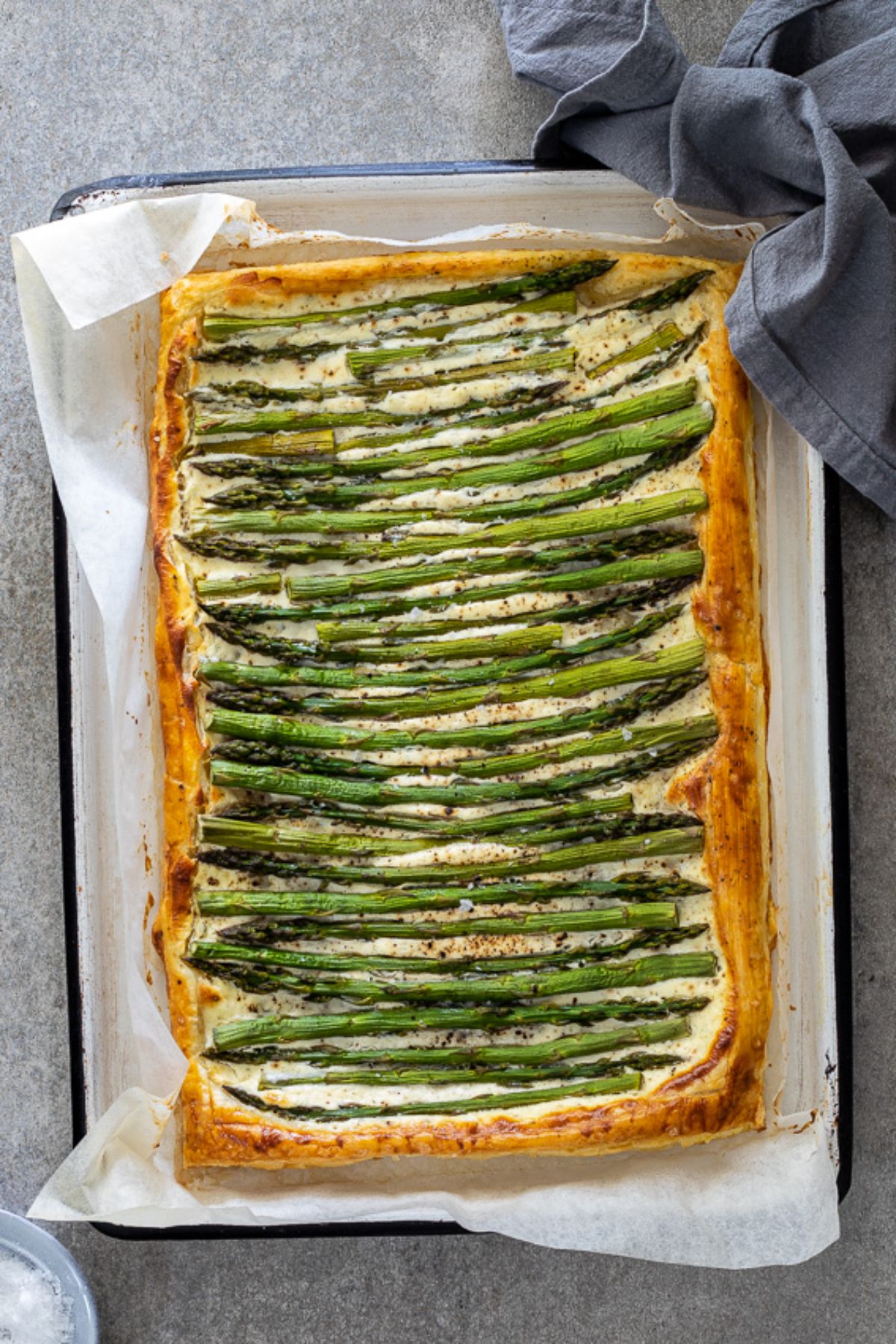 Cripsy cheesy puff pastry asparagus tart on a baking tray.