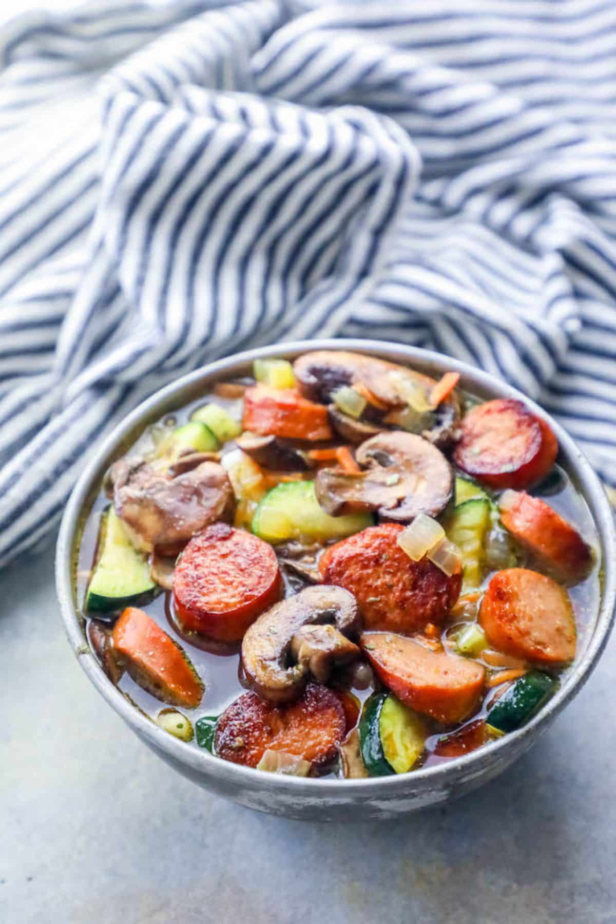 Delicious andouille vegetable soup in a gray bowl.