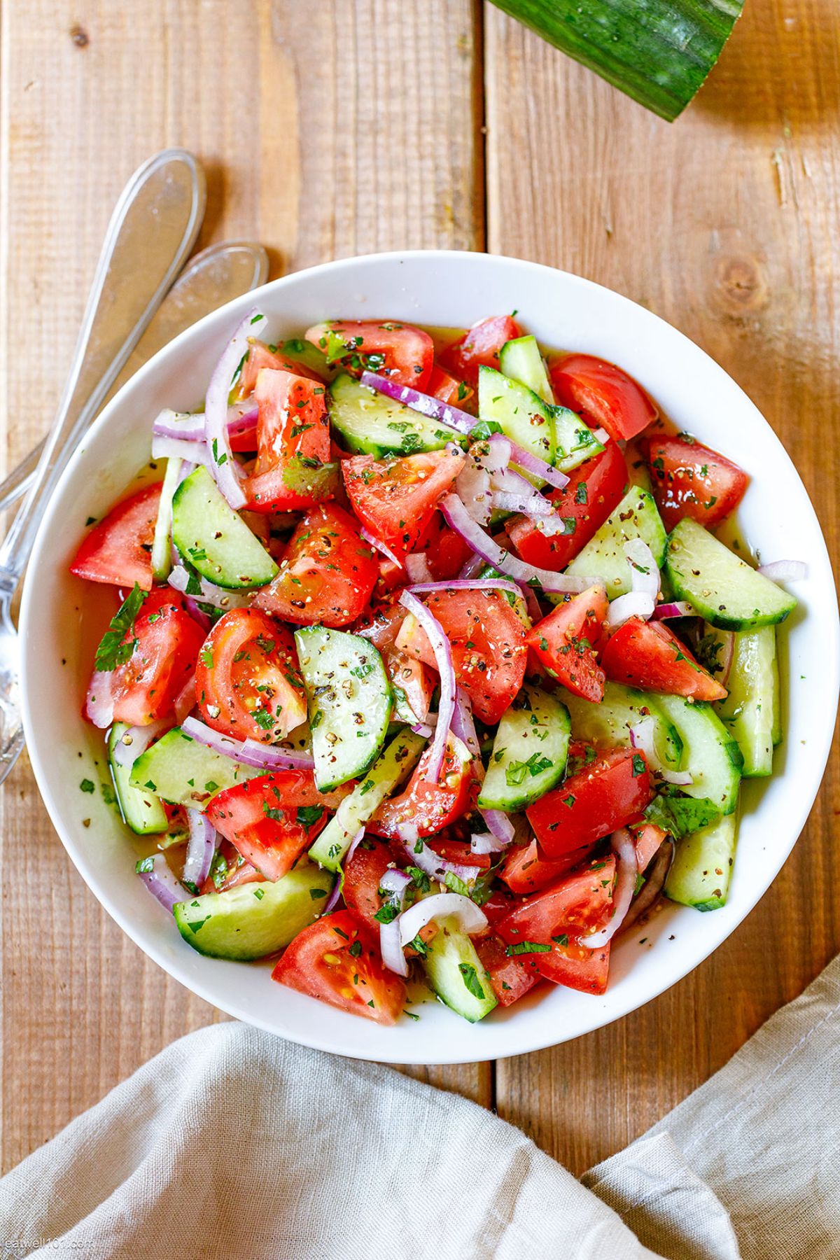 Fresh cucumber tomato salad in a white bowl.