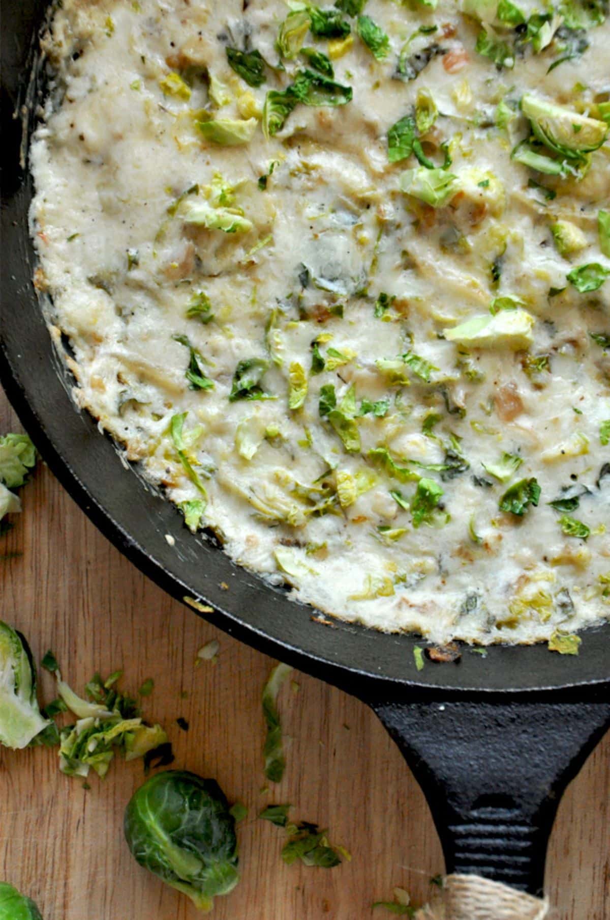 Juicy sour cream brussels sprout & shallot dip in a black skillet.