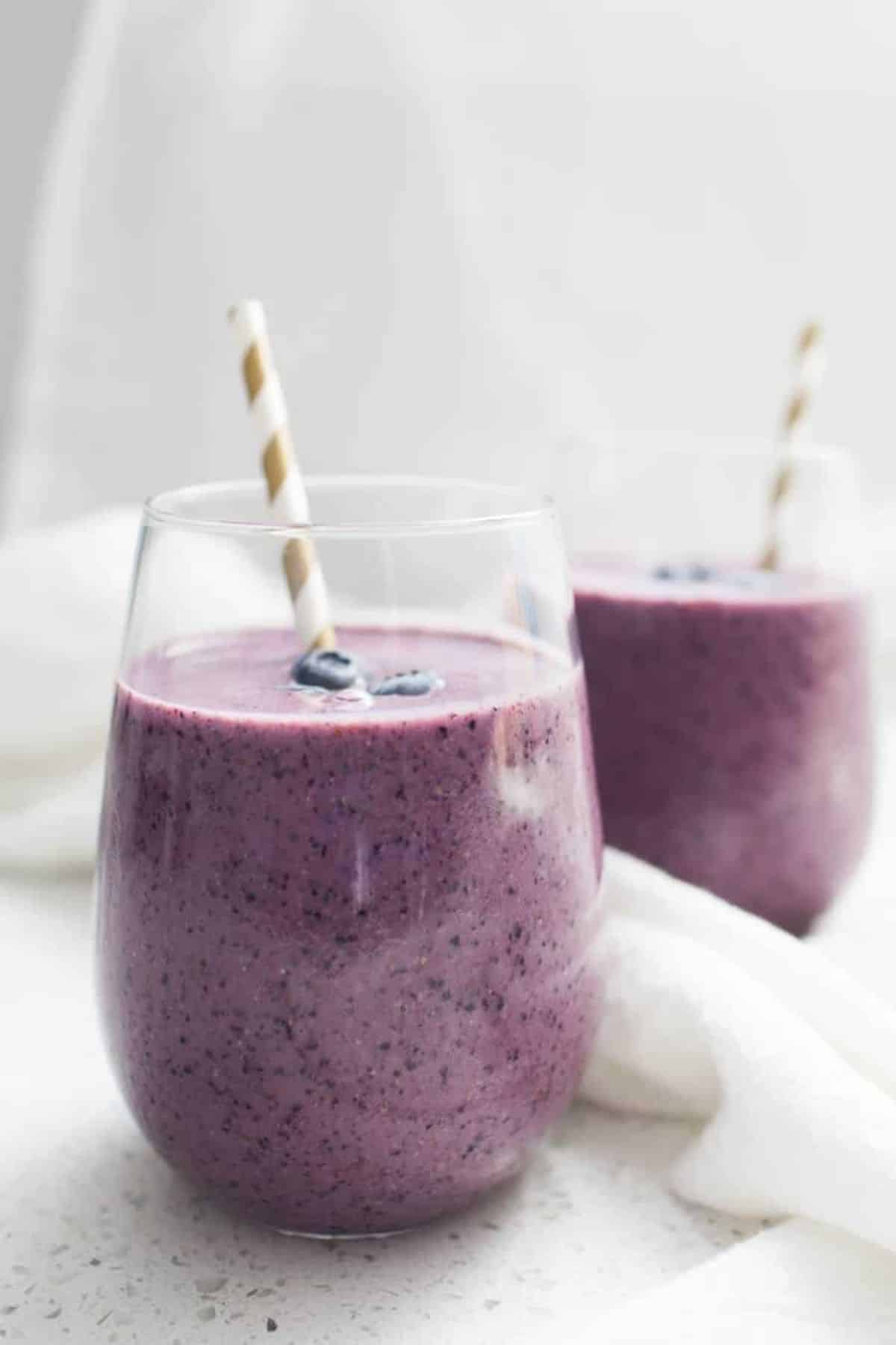 Delicious blueberry greek yogurt smoothie in two glasses with straws.