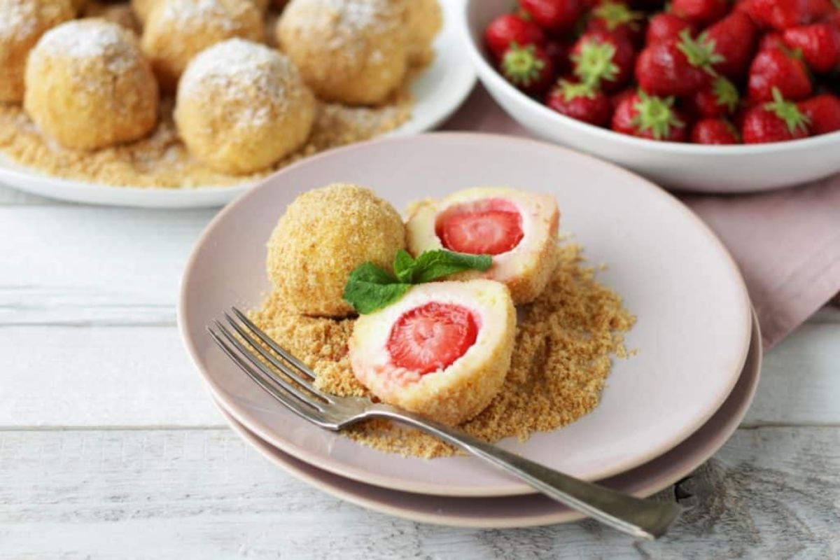 Tasteful strawberry dumplings on a pink plate with a fork.