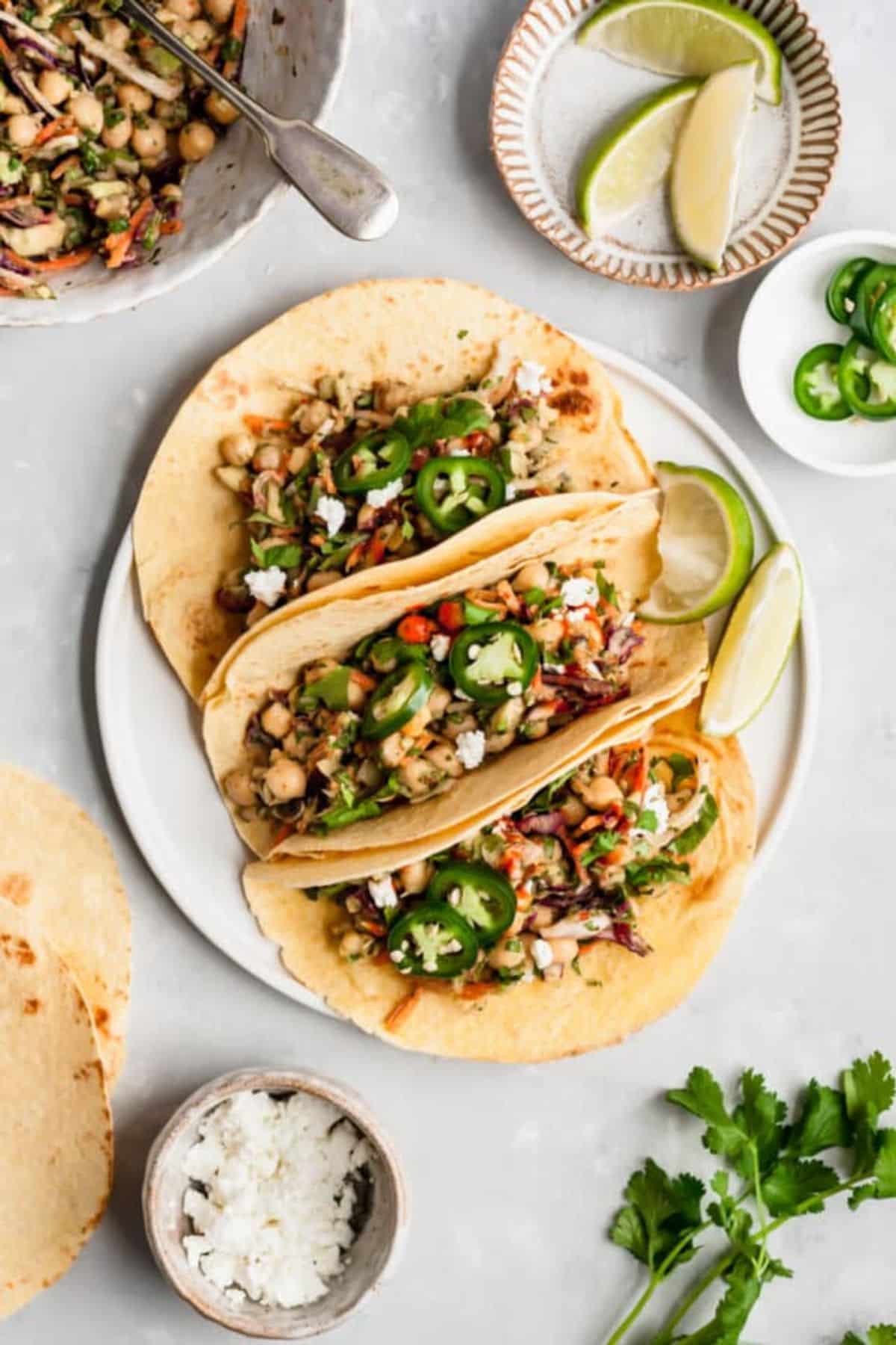 Healthy chickpea and avocado tacos on a white tray.