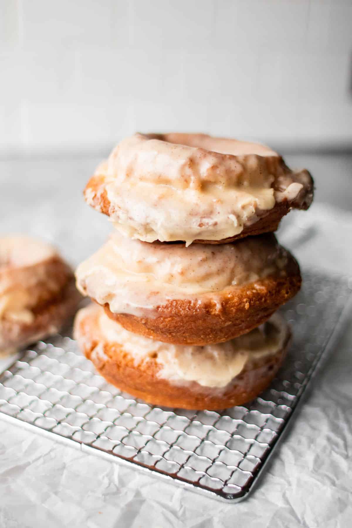 A pile of sour cream donuts with coffee glaze on a resting grid.
