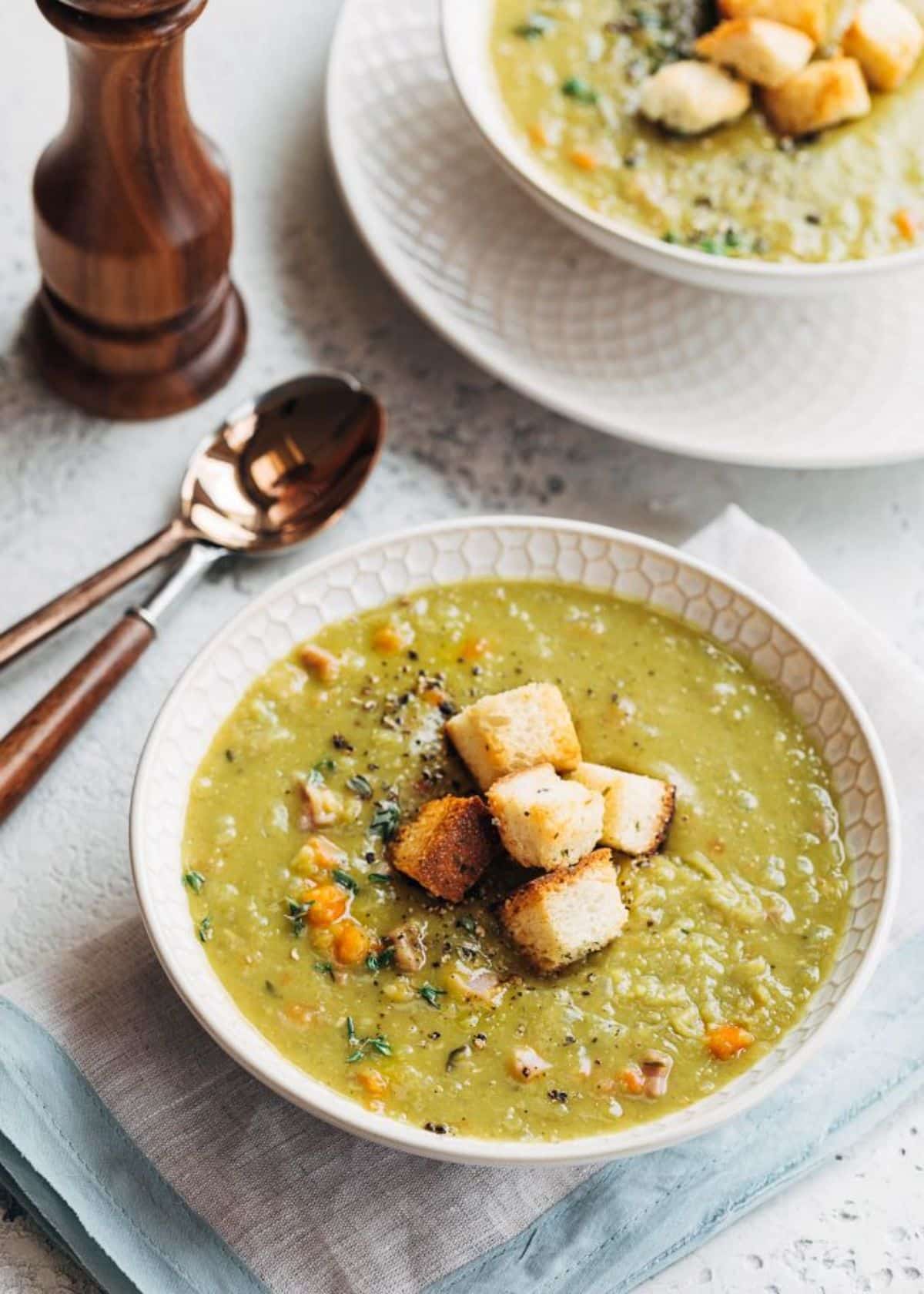 Creamysplit pea soup with ham in a white bowl.