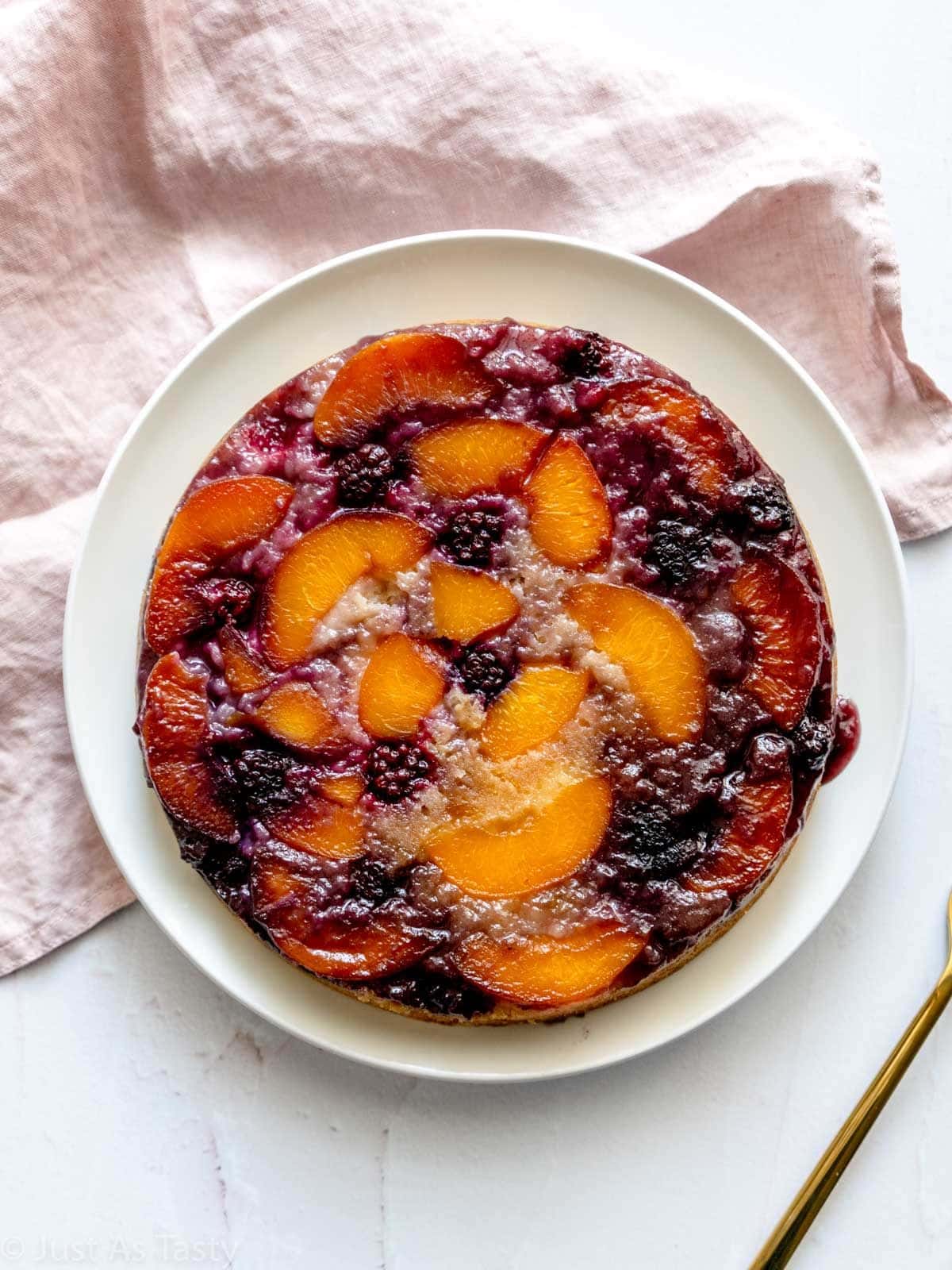 Juicy peach-upside down cake on a white plate.